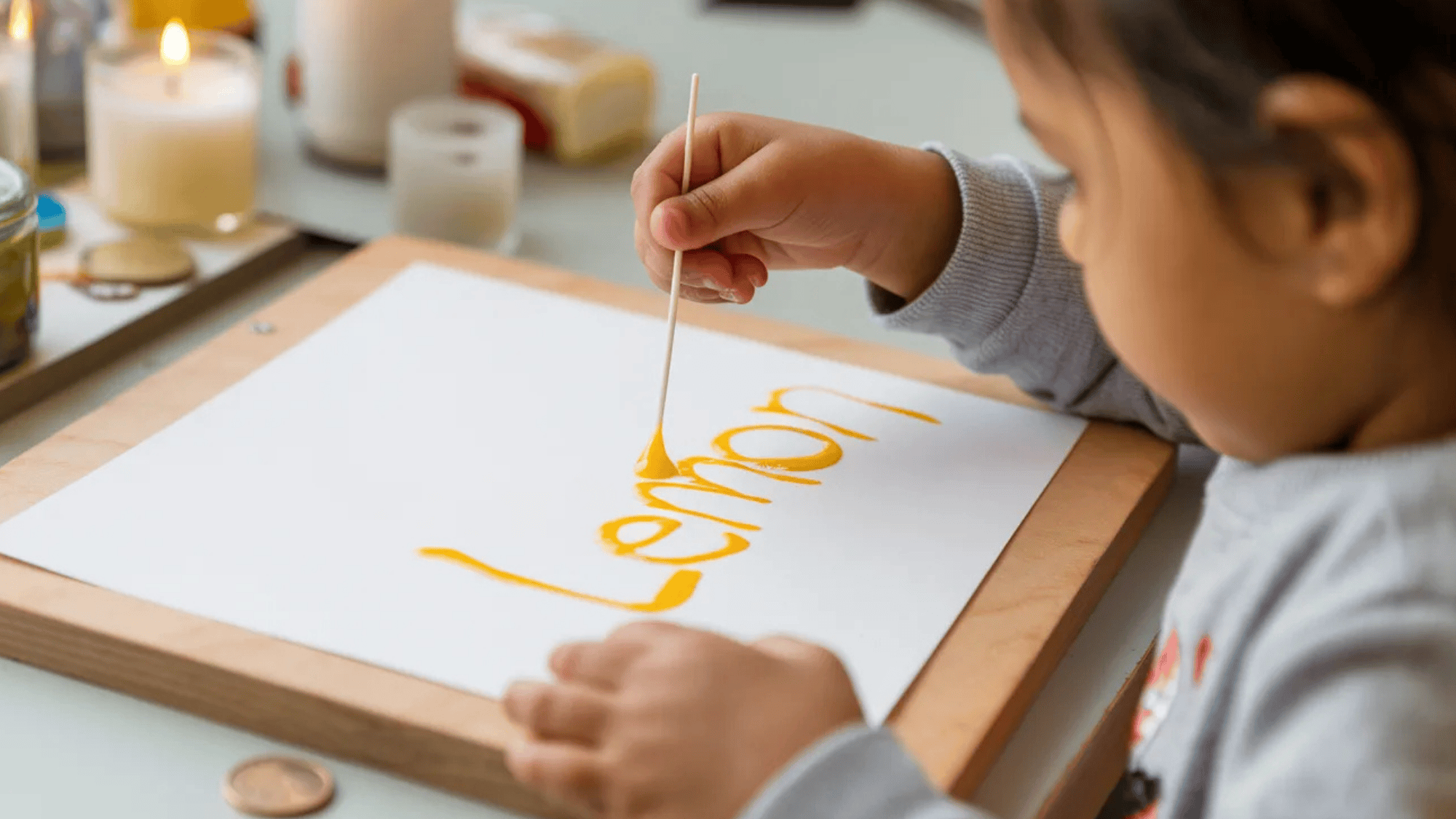 a child writing with a cotton swab and lemon juice