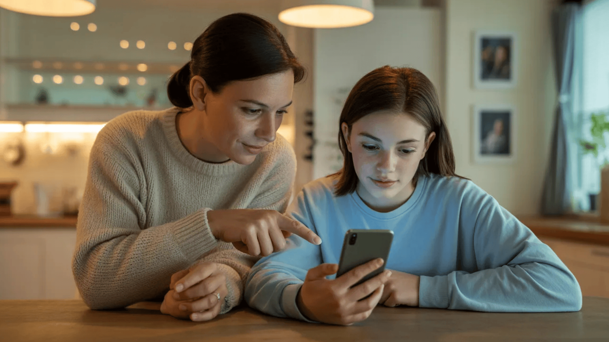 a mother and daughter looking at a phone together, sharing a moment of connection
