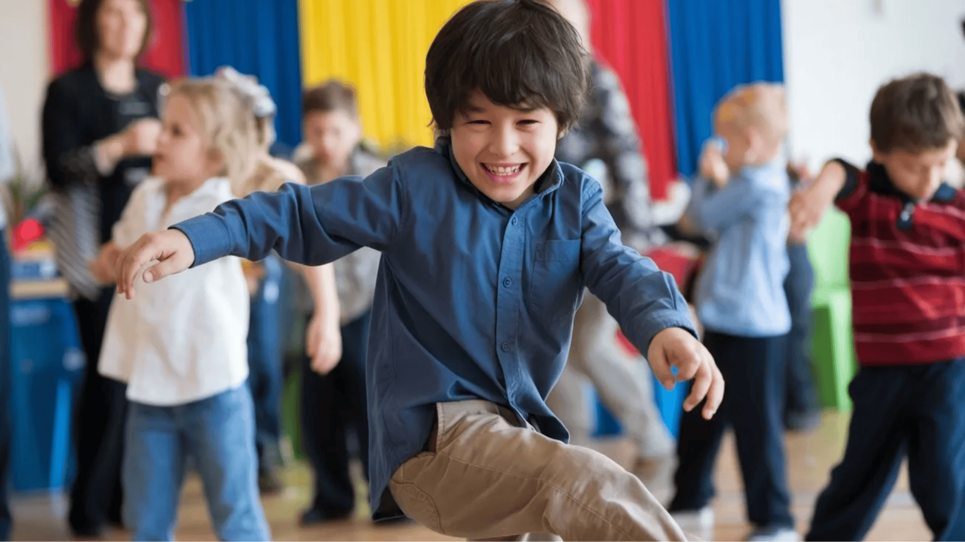 child smiling and freezing mid-dance during a fun freeze dance game with other kids in the background