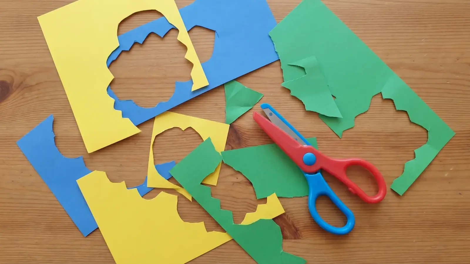 Child-safe scissors with paper pieces showing repeated uneven and off-track cuts