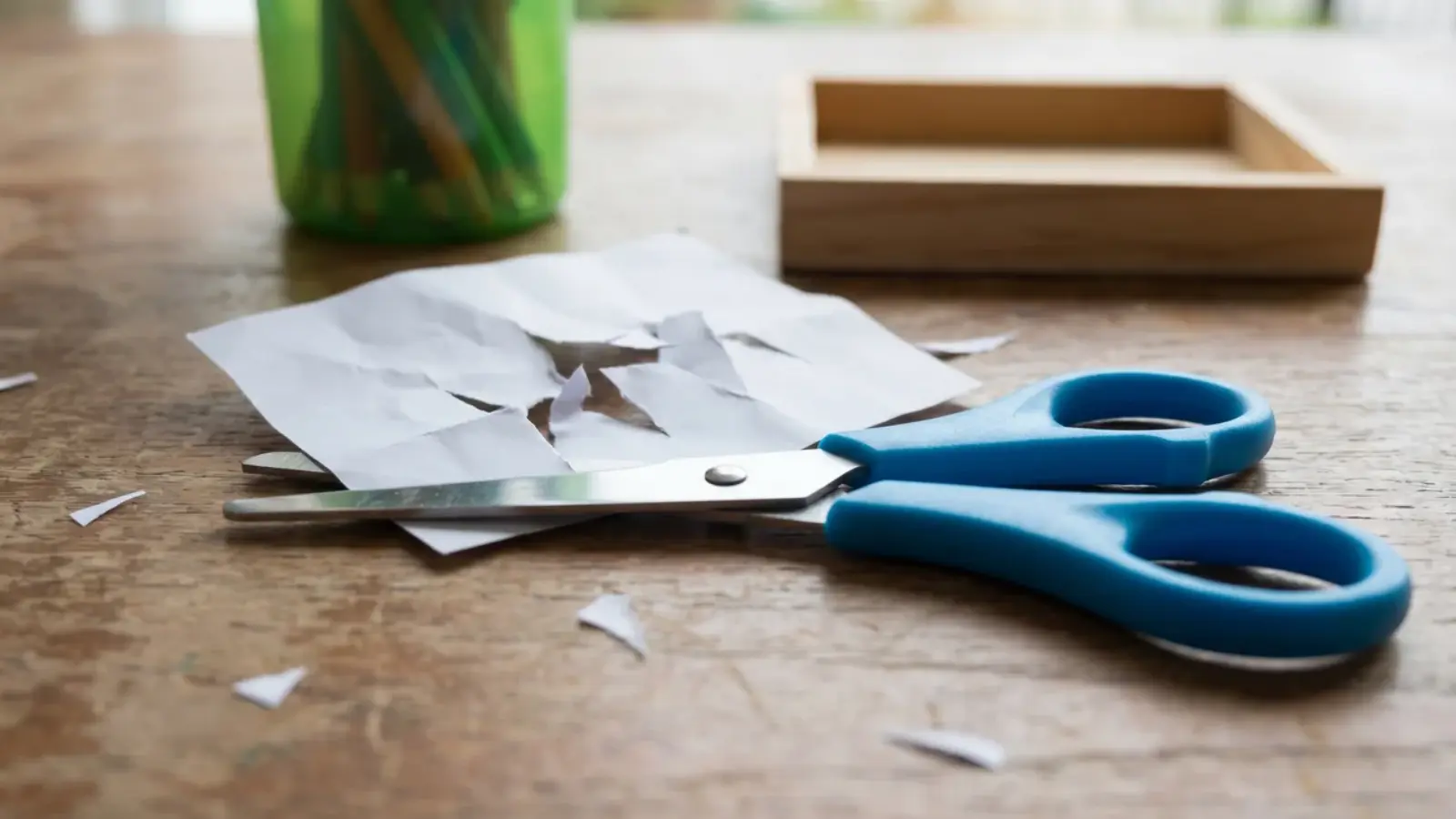 Child-safe scissors with uneven paper snips showing early cutting attempts