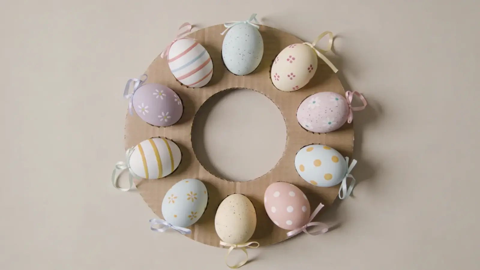 Circular wreath made from cardboard with decorated eggs attached evenly around the ring