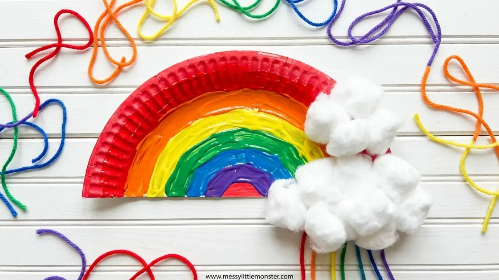 Paper plate rainbow craft with cotton clouds and colorful yarn strands