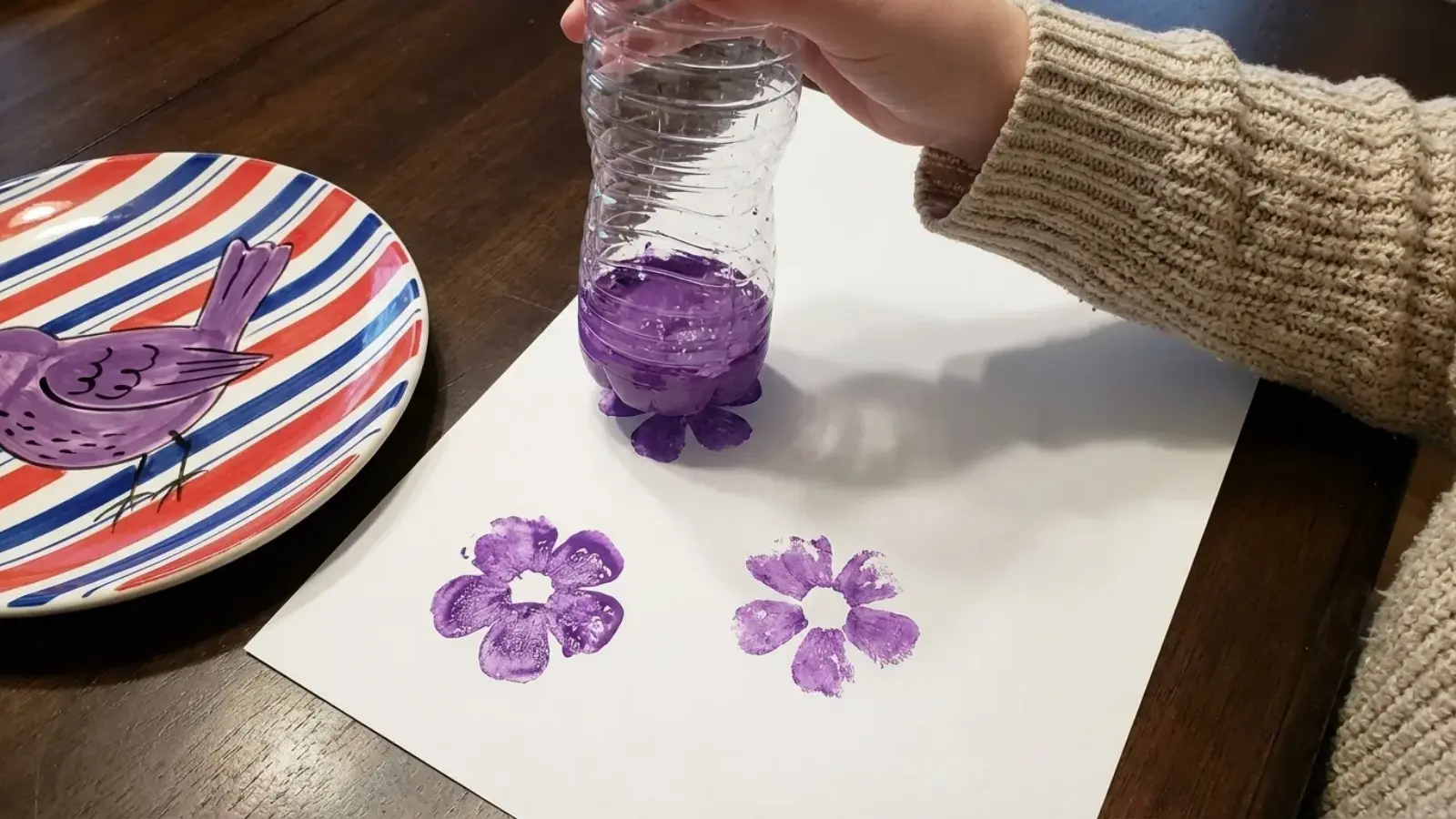 Plastic bottle dipped in paint stamping flower shapes on paper