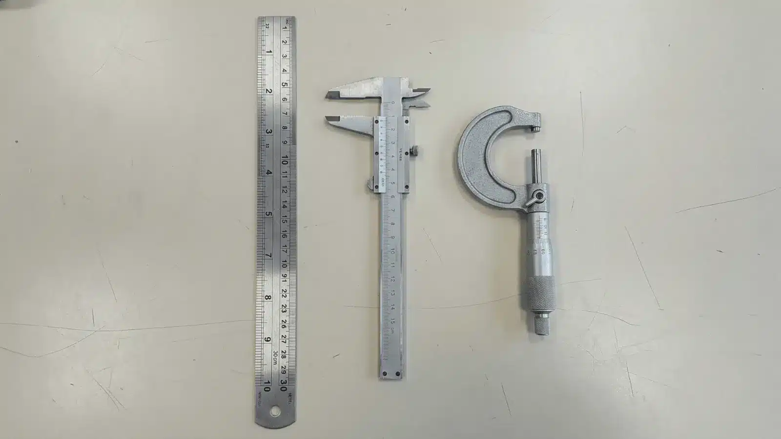 Ruler, vernier caliper, and micrometer arranged to show different measurement precision levels