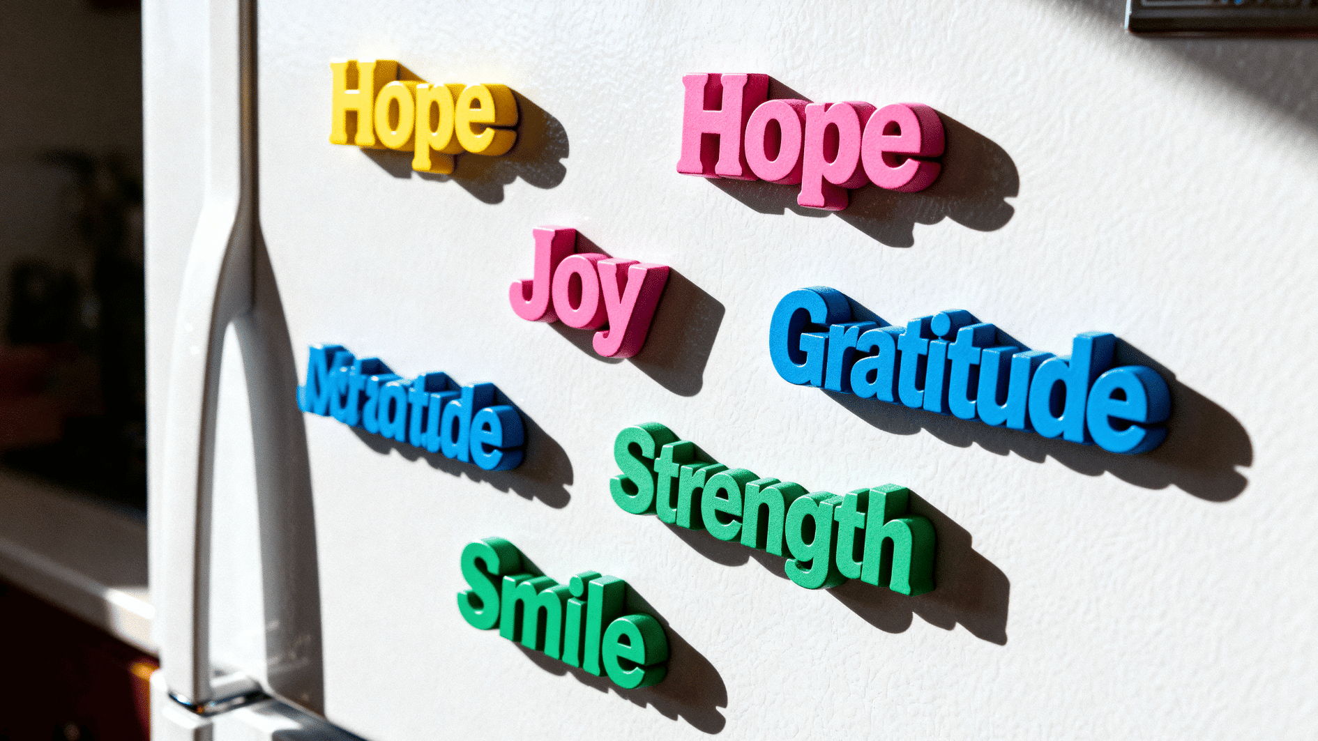 colorful magnetic words like hope, joy, gratitude, strength, and smile arranged on a fridge in bright light