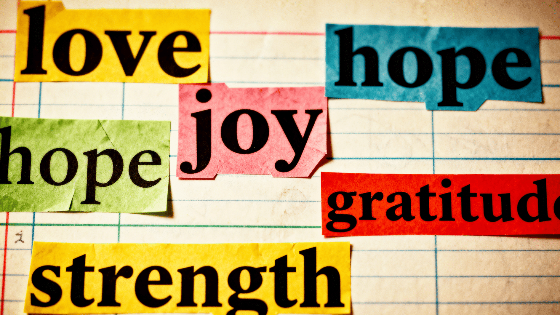 cutout words like love, joy, hope, gratitude, and strength arranged on lined paper background
