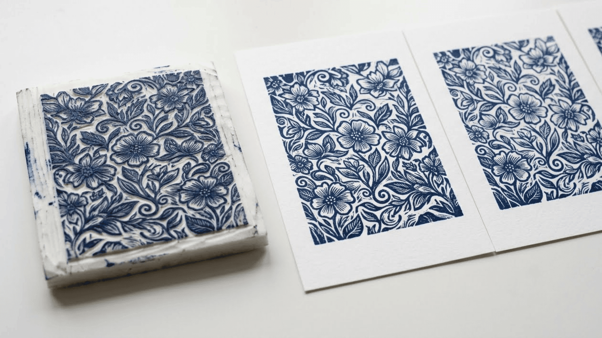 mini printmaking foam plate with etched floral design next to navy blue printed impressions on a plain white surface