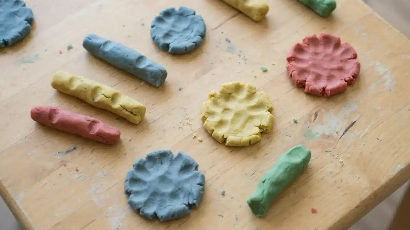 Playdough pieces rolled and flattened on a table showing hand squeezing activity