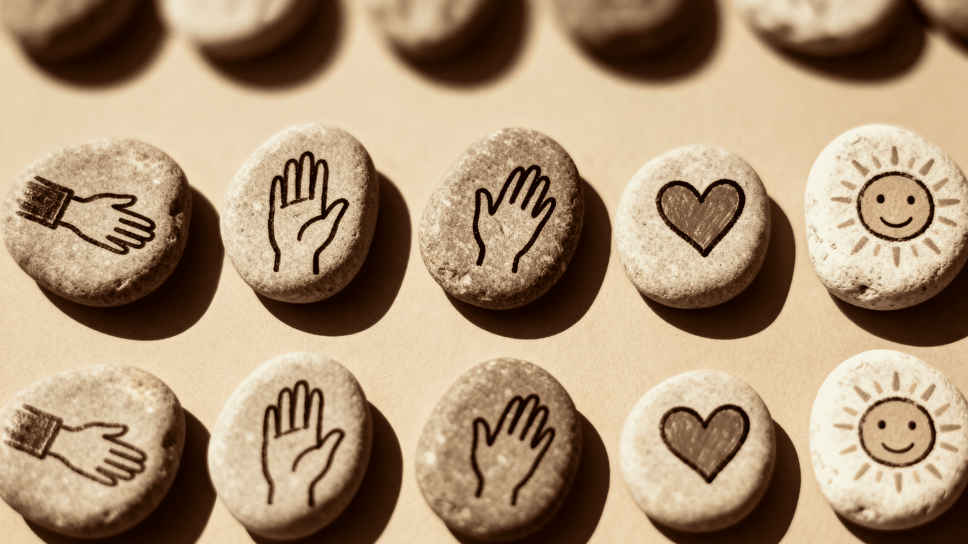 smooth stones with symbols like hands, heart, and sun engraved, neatly arranged in rows