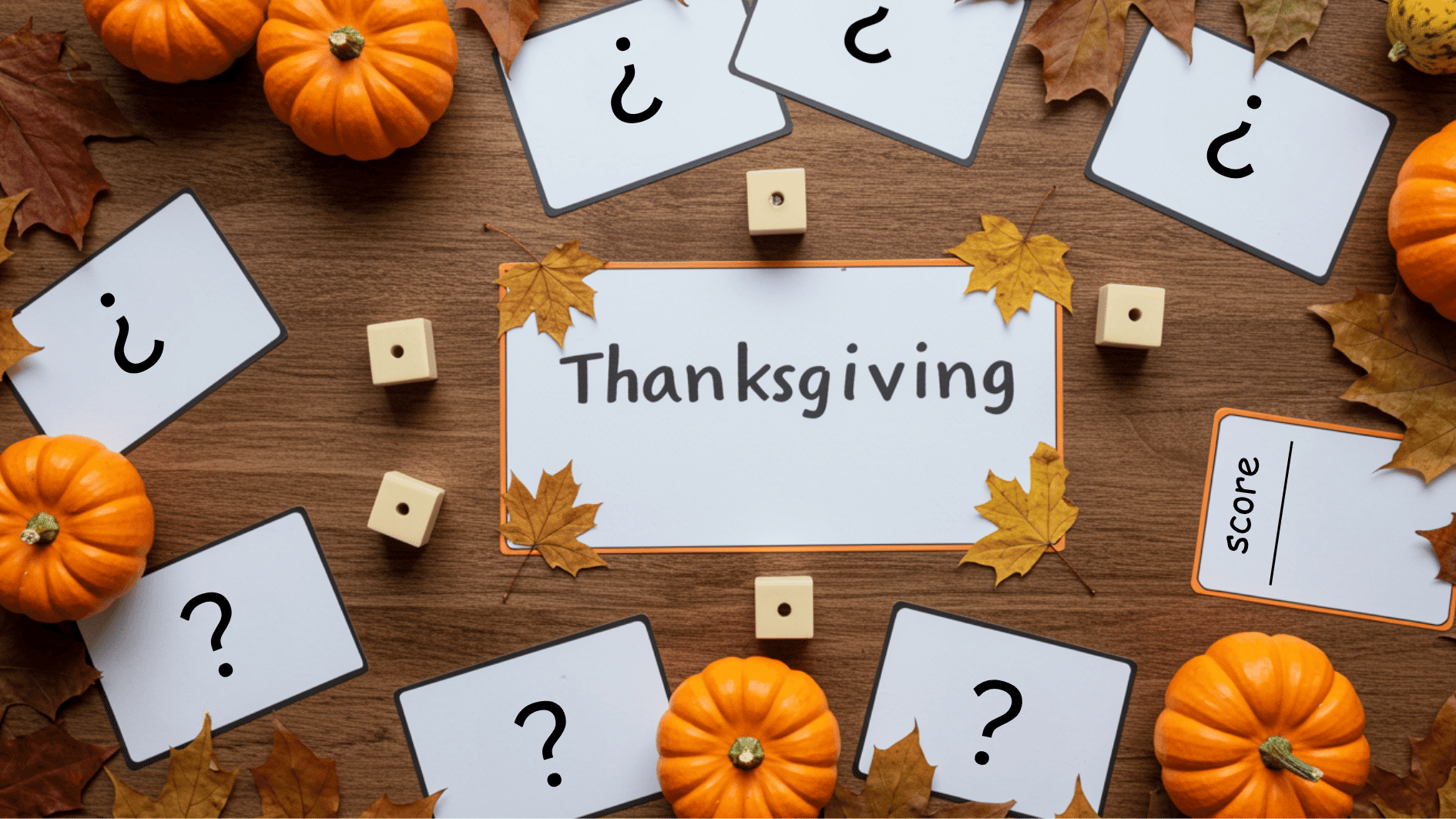thanksgiving game setup with cards, dice, pumpkins, and leaves arranged on wooden table for festive family activities