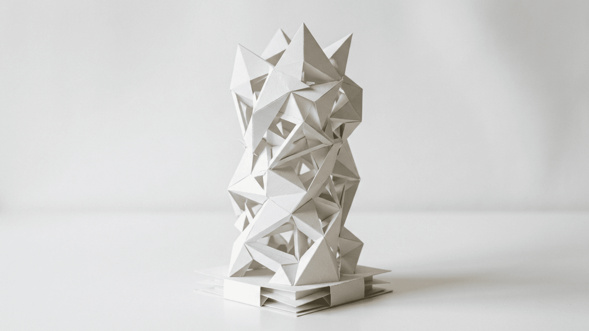 three dimensional paper sculpture made from folded and layered white cardstock forming an abstract geometric tower