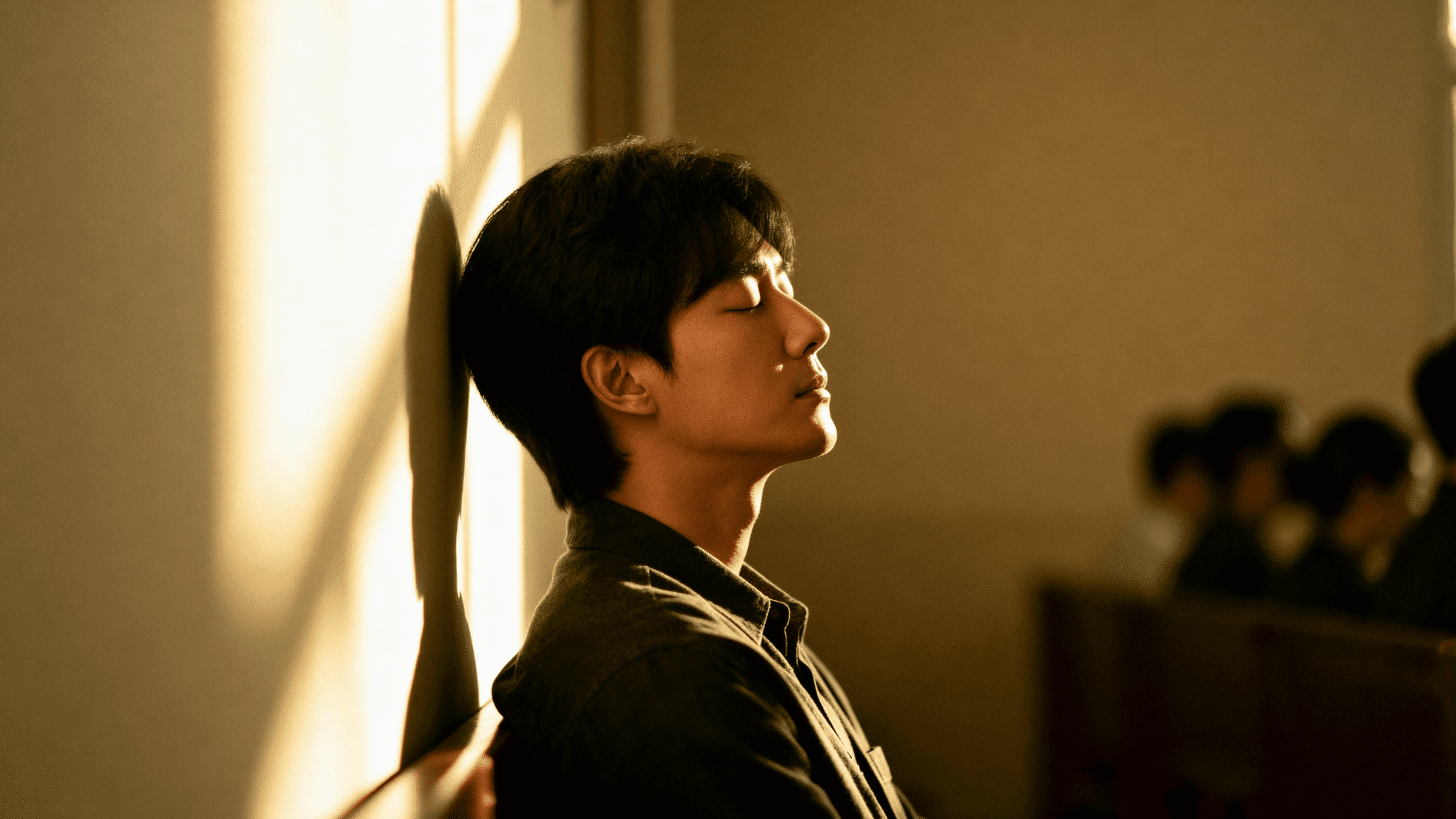 young man leans against wall with eyes closed, reflecting, managing stress, and setting emotional boundaries in a quiet space