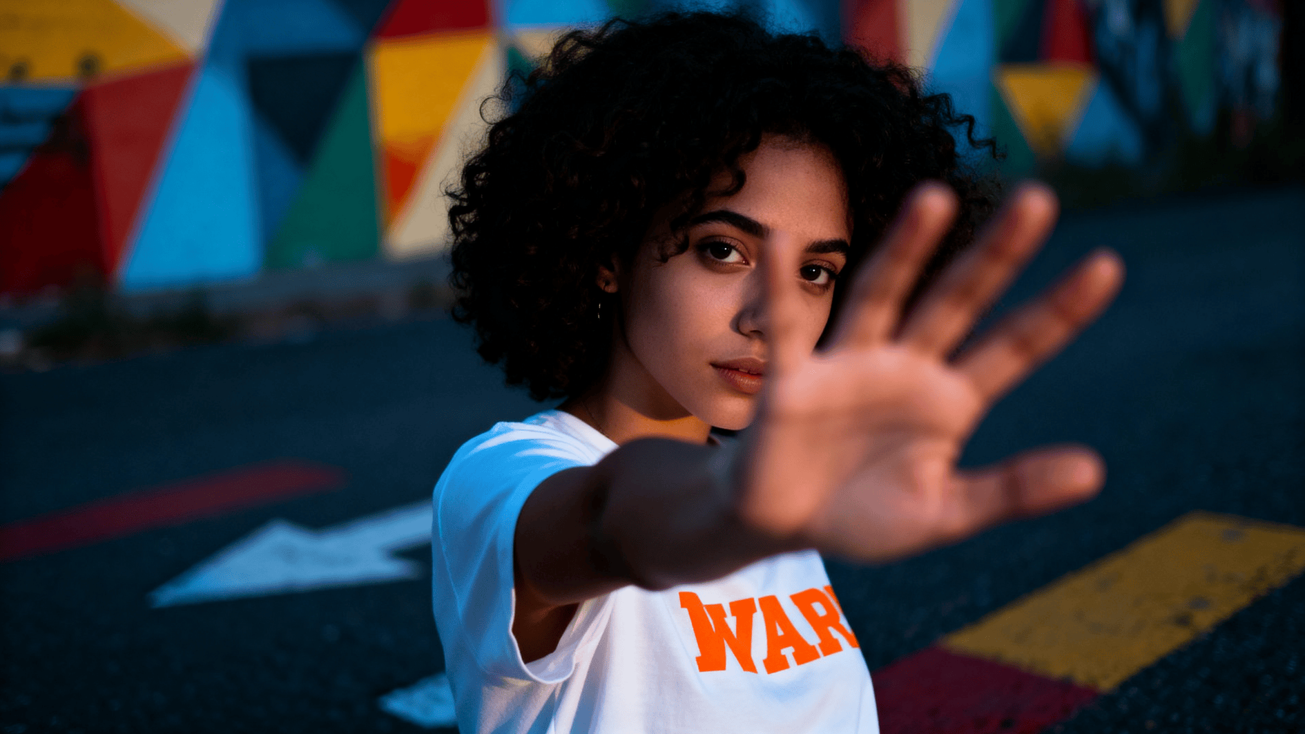 young woman raises hand in stop gesture, expressing assertiveness, setting boundaries, and protecting personal space in social setting
