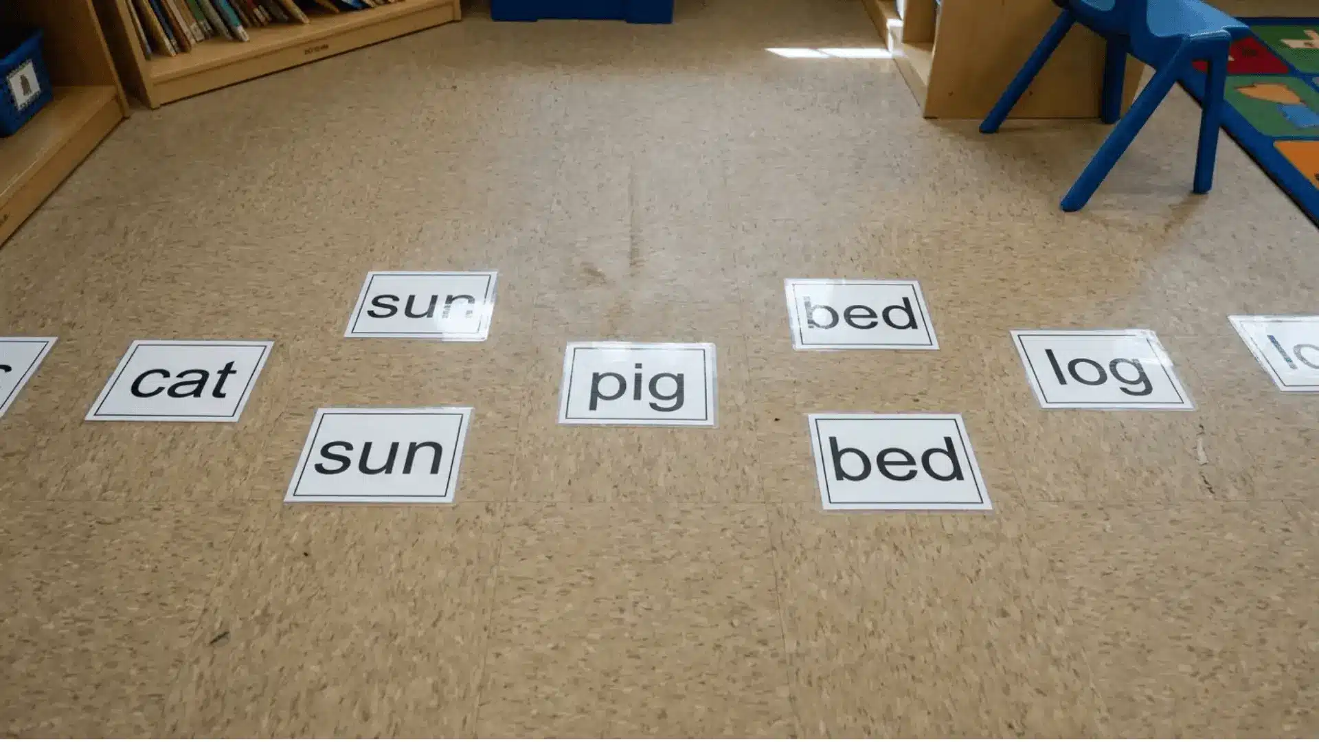 CVC word cards placed on a classroom floor for a phonics hop game activity.