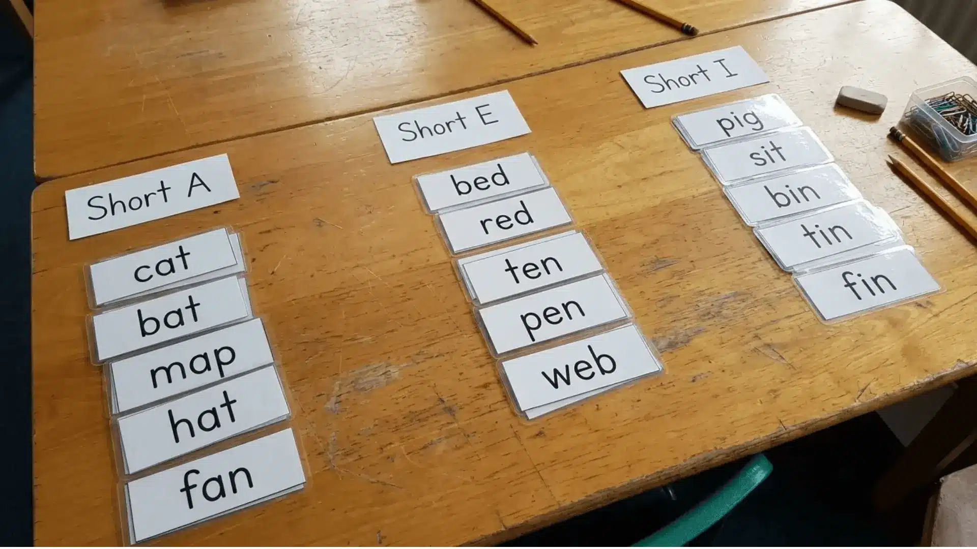 CVC word cards sorted into groups by vowel sounds on a classroom table.