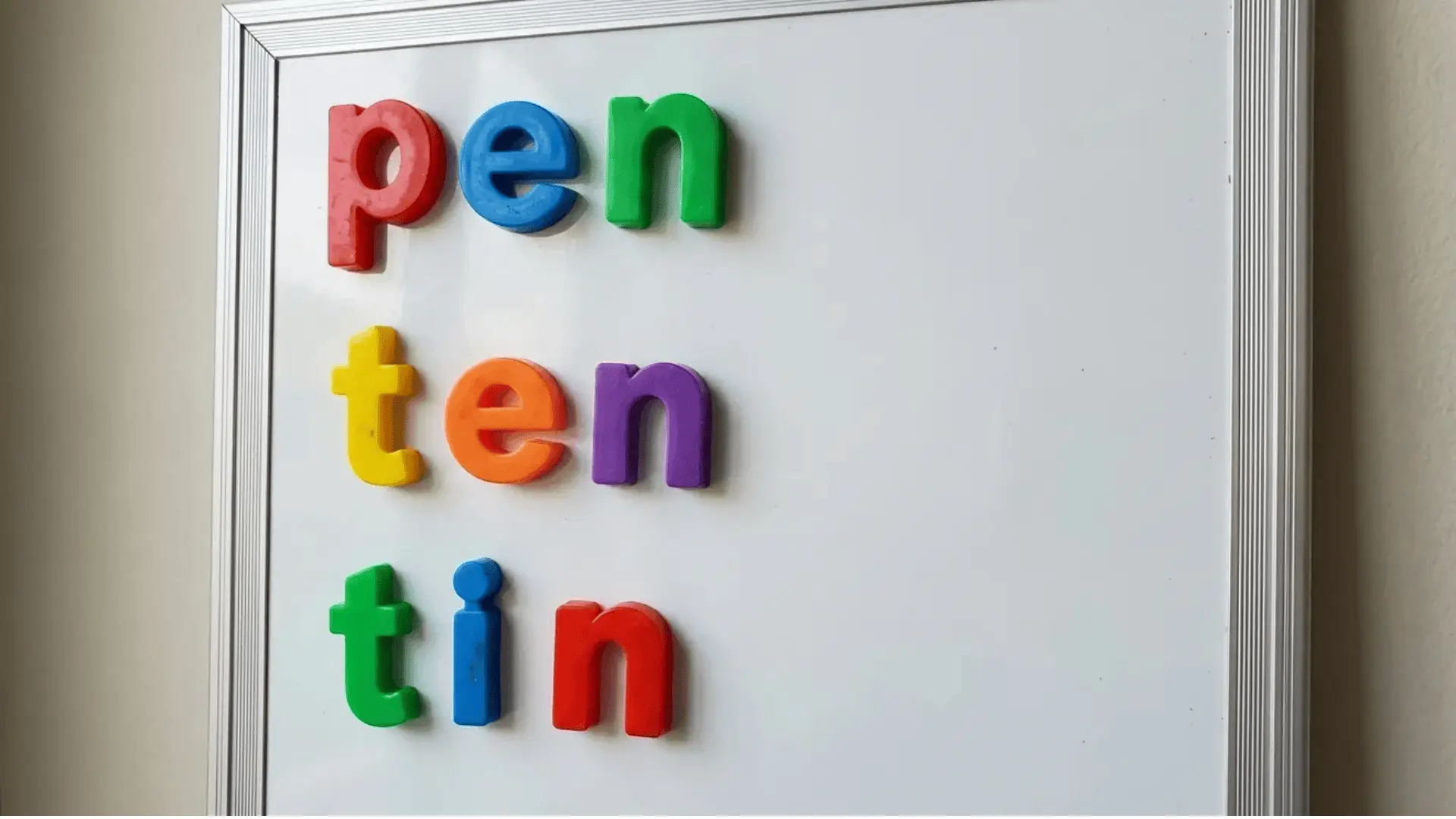 Magnetic letters on a board forming the CVC words pen, ten, and tin.