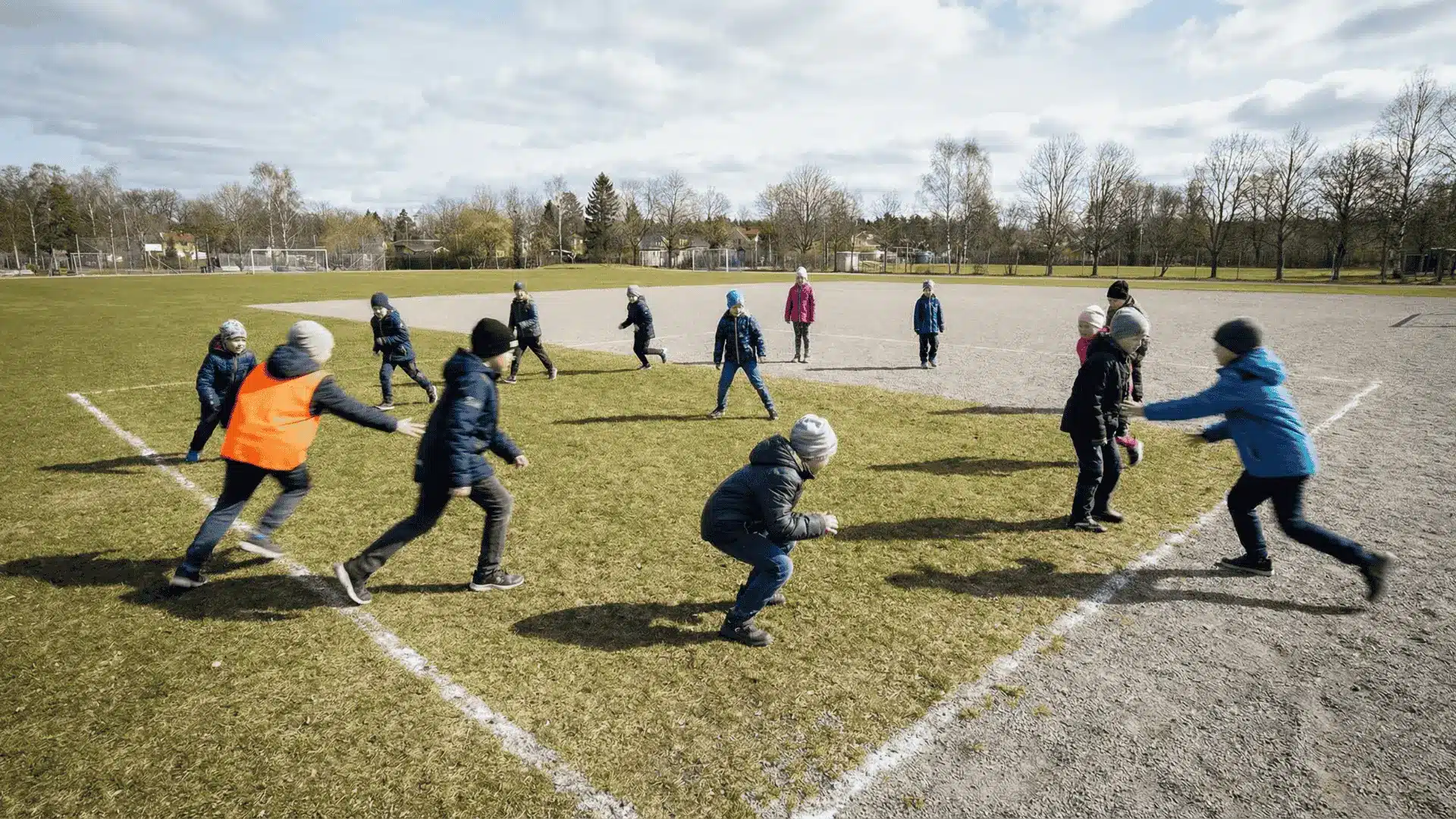 Children standing frozen while others move around tagging them in an open play area