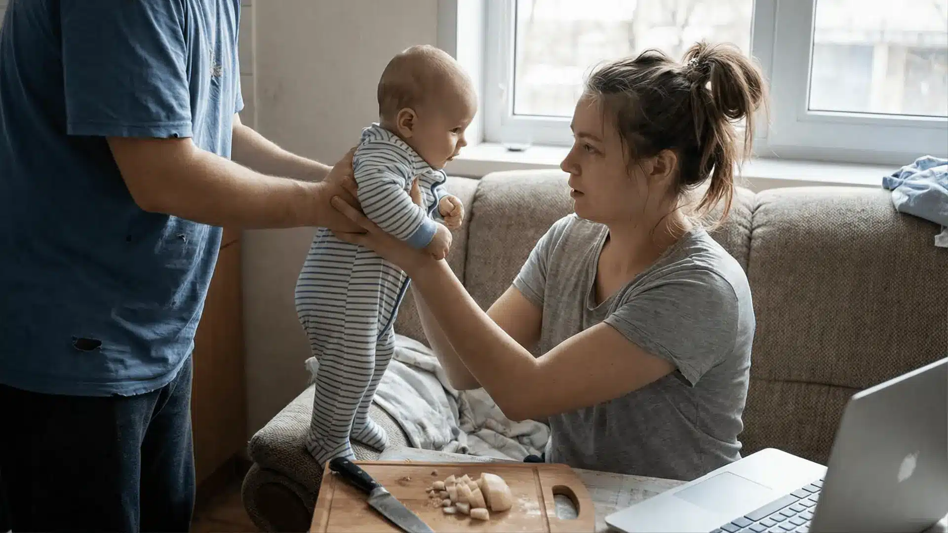 One adult handing a newborn to another in a home setting