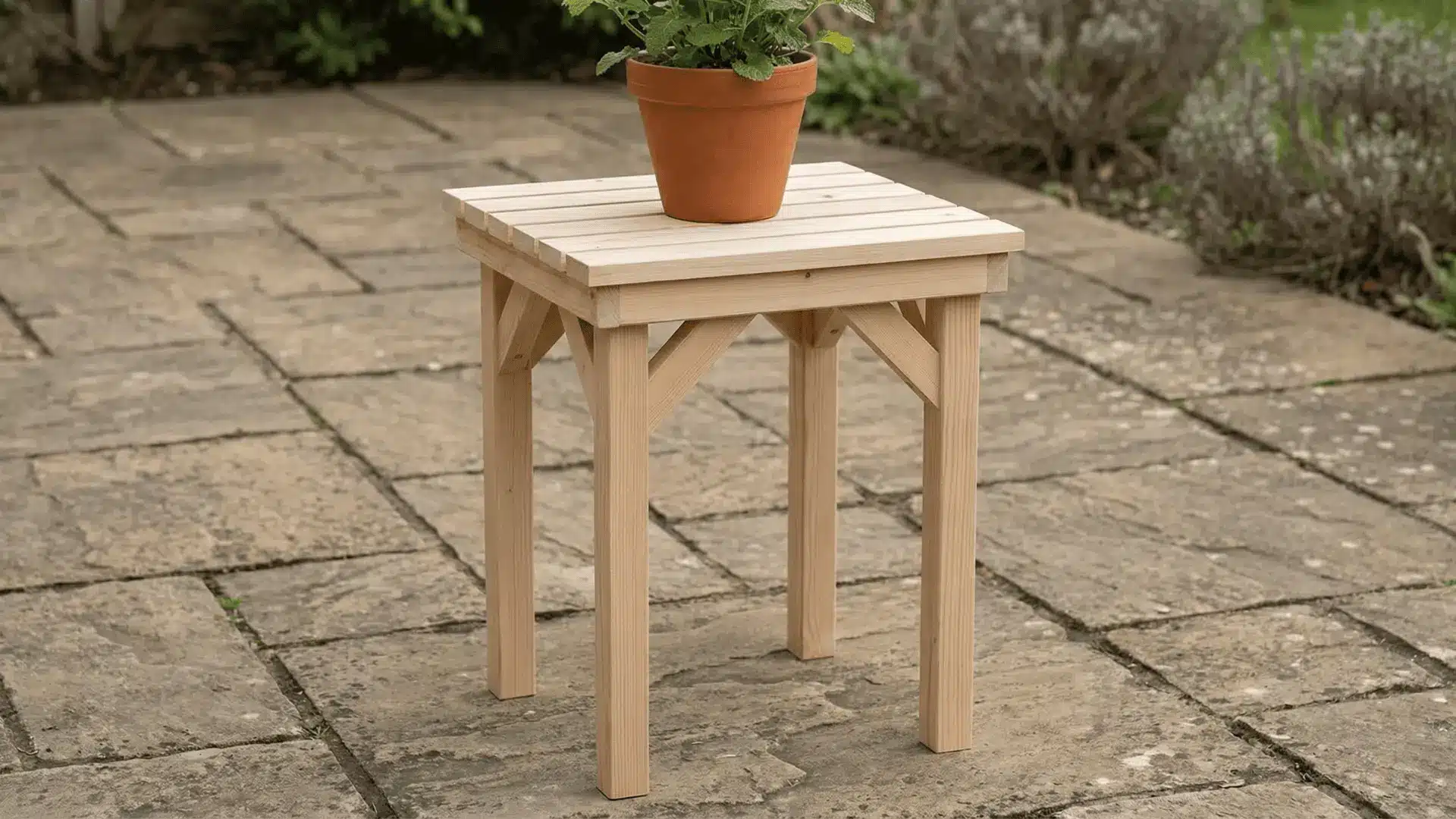 Wooden plant stand with four legs holding a plant pot on an outdoor patio surface