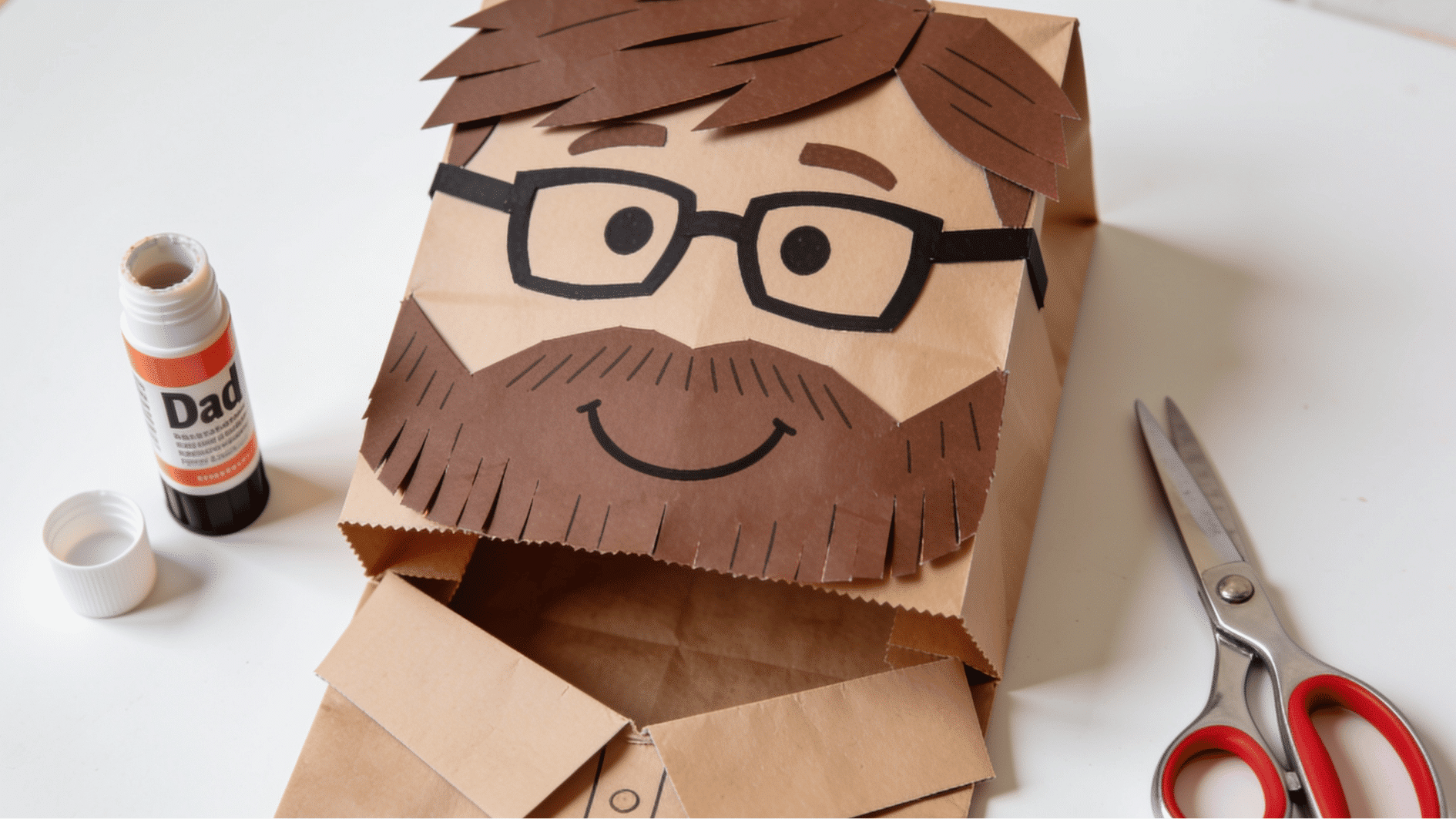 brown paper bag dad puppet with construction paper hair beard glasses and shirt collar fathers day craft for kids