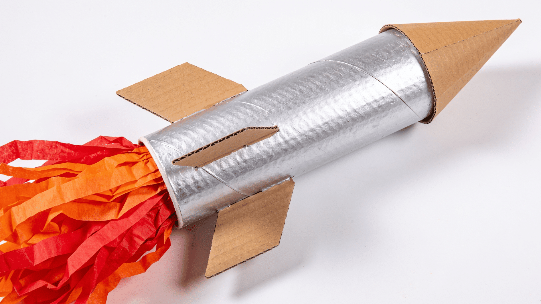 cardboard roll rocket in silver and red with a cone top cardboard fins and tissue paper flames