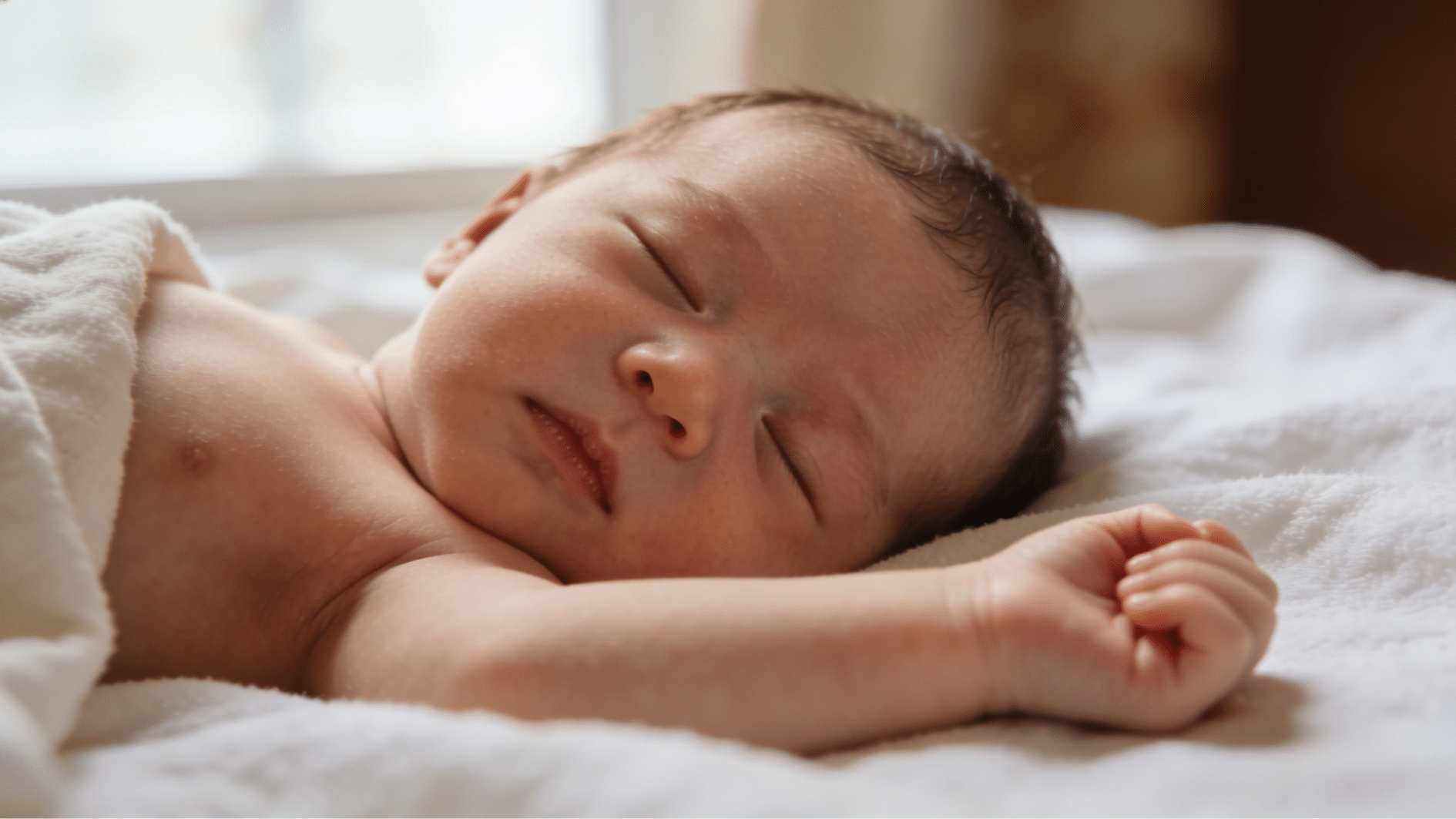 close up of a sleeping newborn with tiny fists resting freely on a soft white blanket (85 characters)
