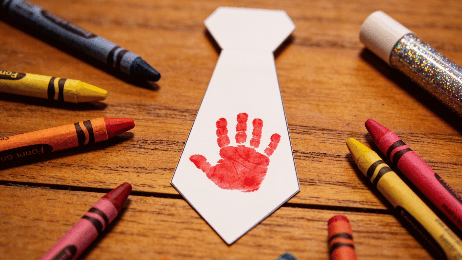 fathers day handprint tie card made from white cardstock with red painted toddler handprint on wooden table