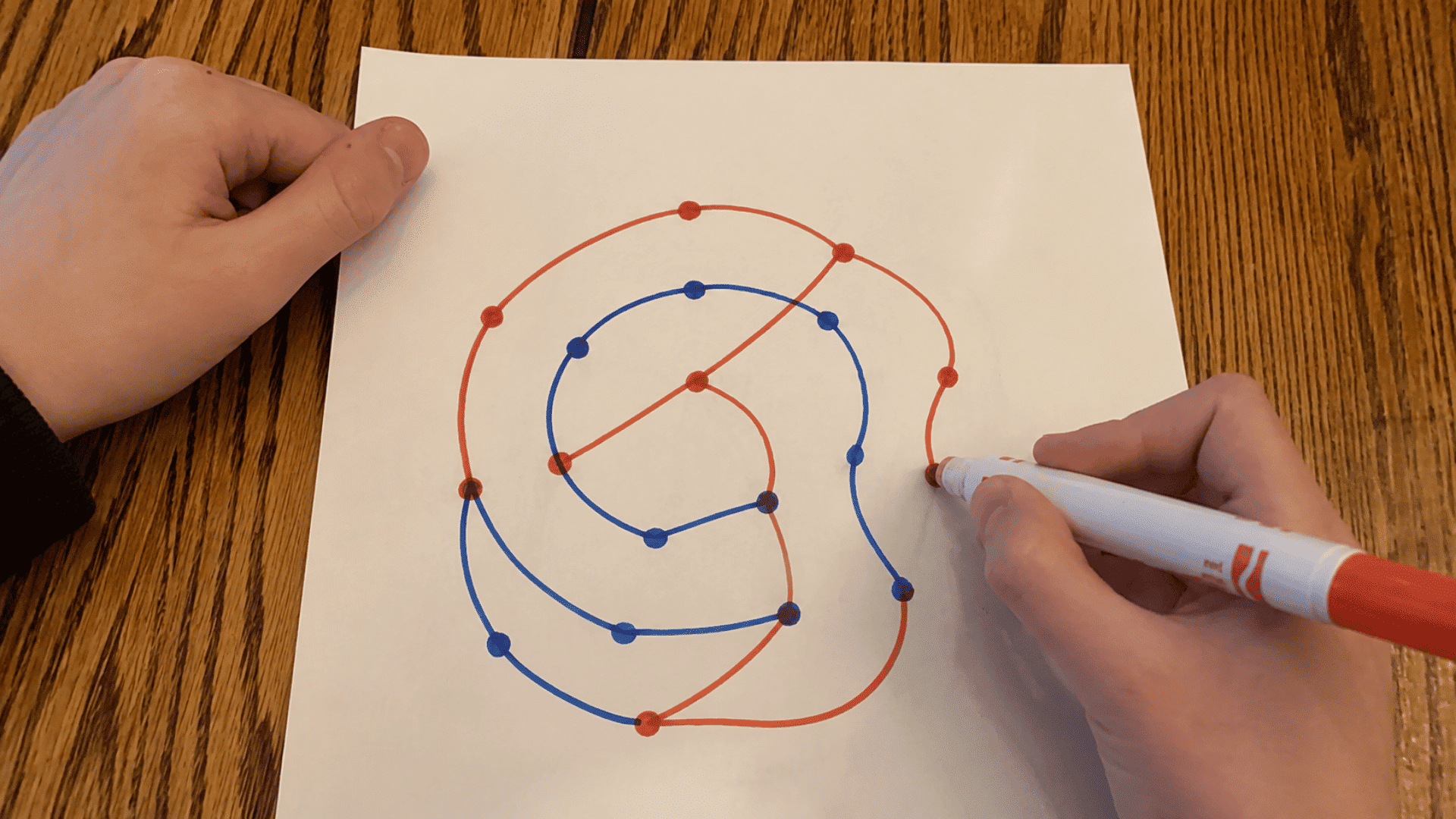 pen and paper game with setup image of sprouts game paper and red and blue sketch setup and style and a hand drawing the sprouts