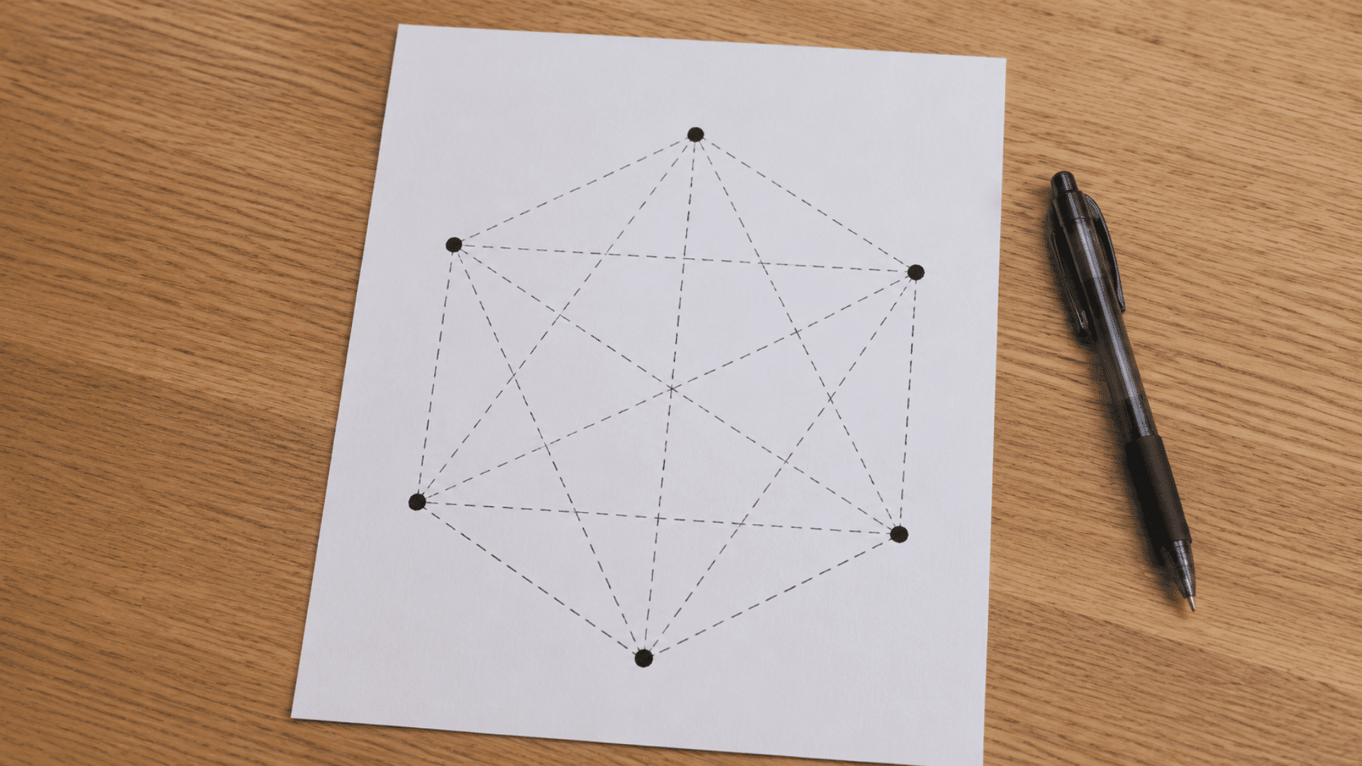 sim game setup pen and paper game setup on a wooden table showing geometric shapes dotted lines and black oen
