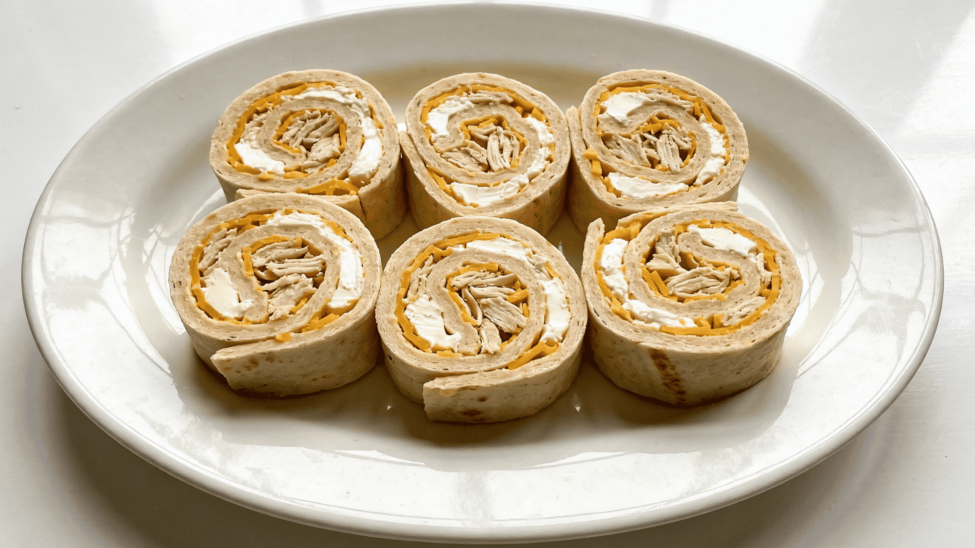 six chicken and cheese tortilla pinwheel rounds showing cream cheese and cheddar filling