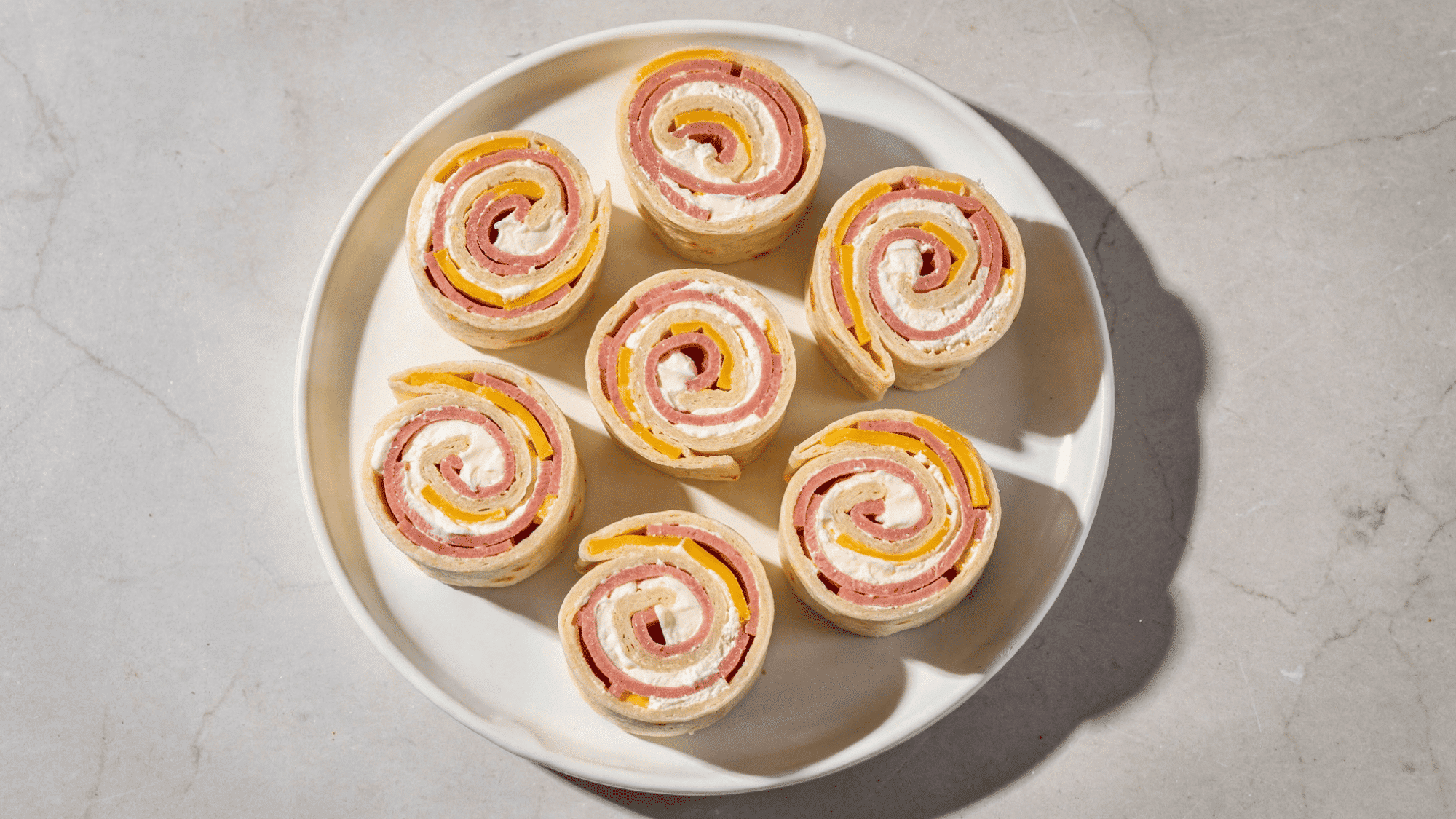 six spiral ham and cheese pinwheel rounds showing cream cheese and cheddar layers