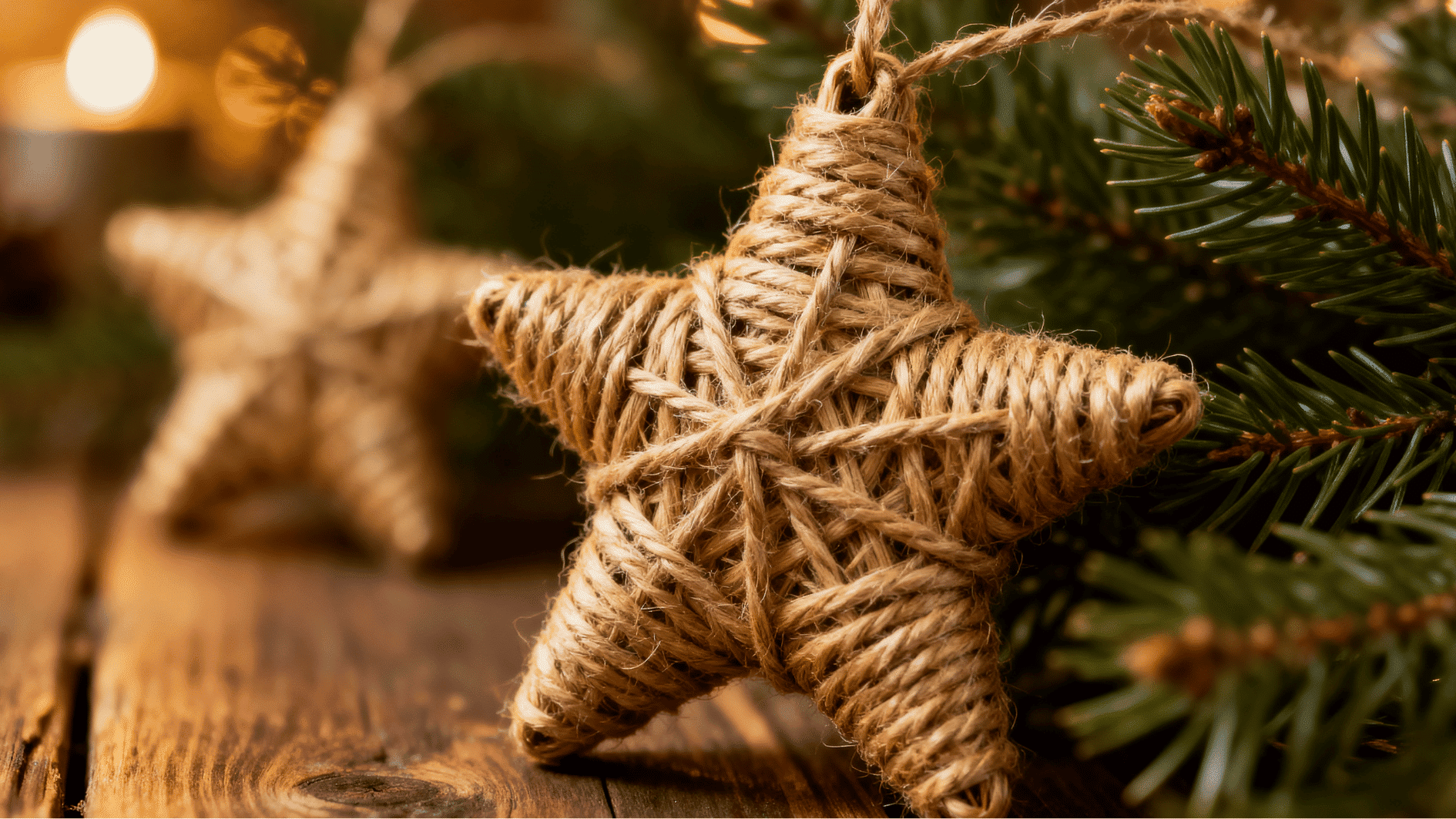 burlap rope star ornament close up hanging on pine branch rustic wood background warm holiday lights bokeh cozy decor