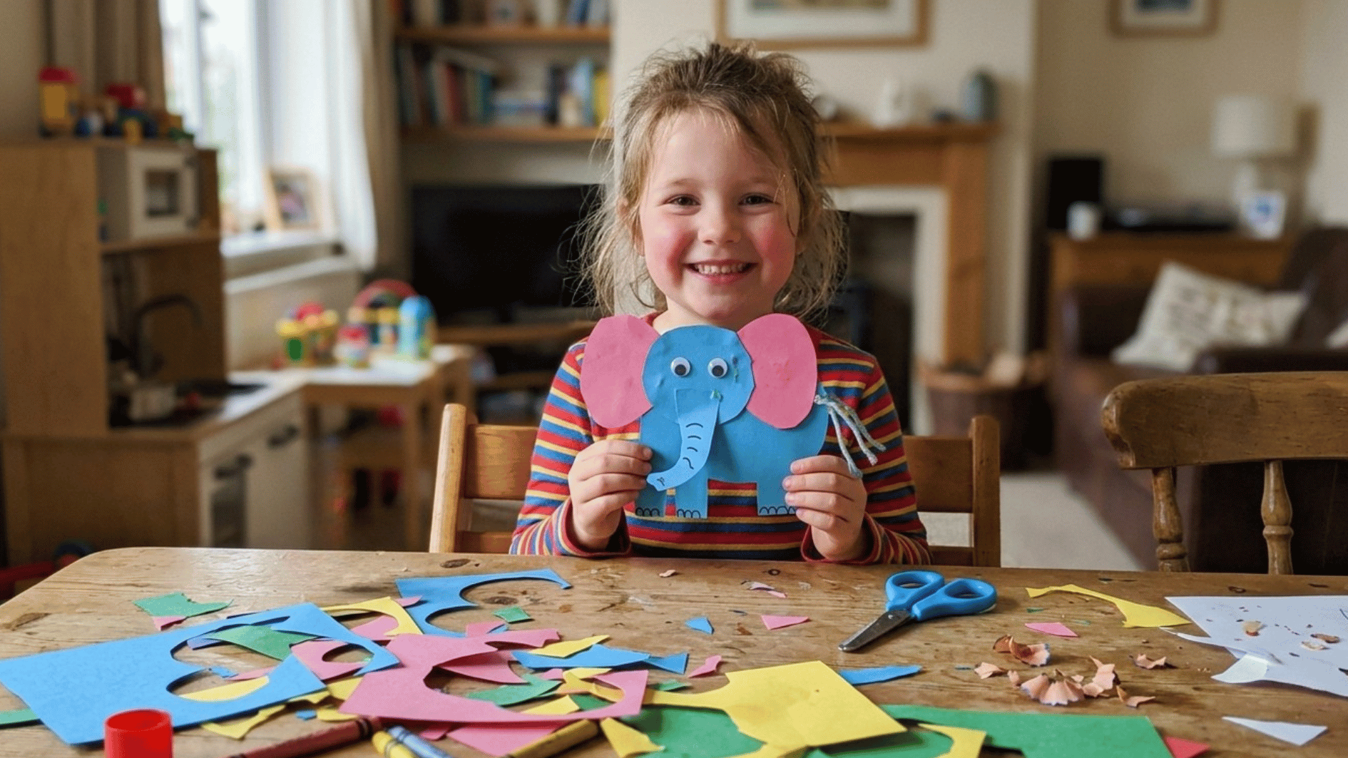 child creating a colorful paper elephant craft at a table with scissors glue and craft materials at home