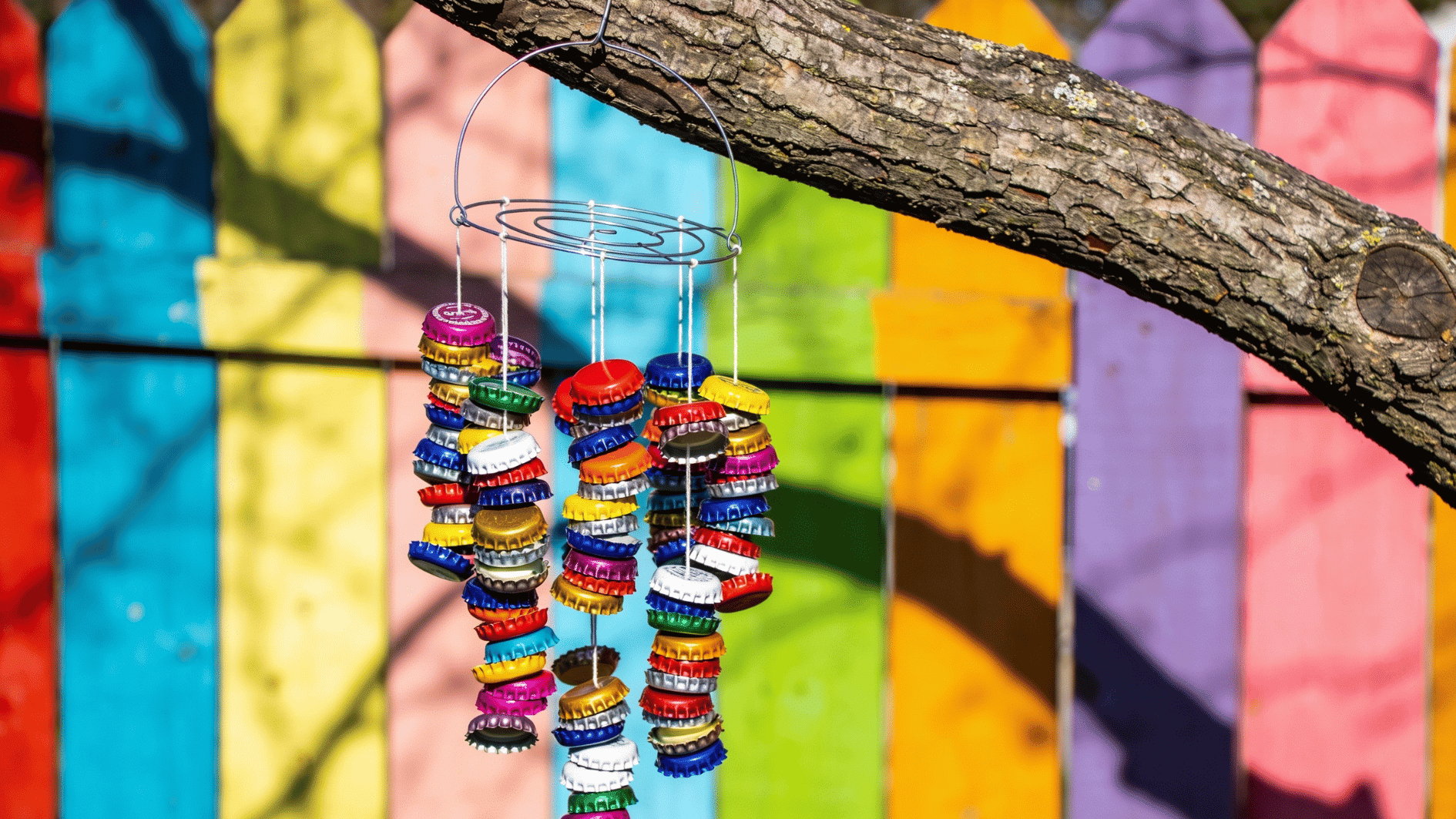Colorful bottle cap wind chime with stacked caps on wire strands hanging from a branch