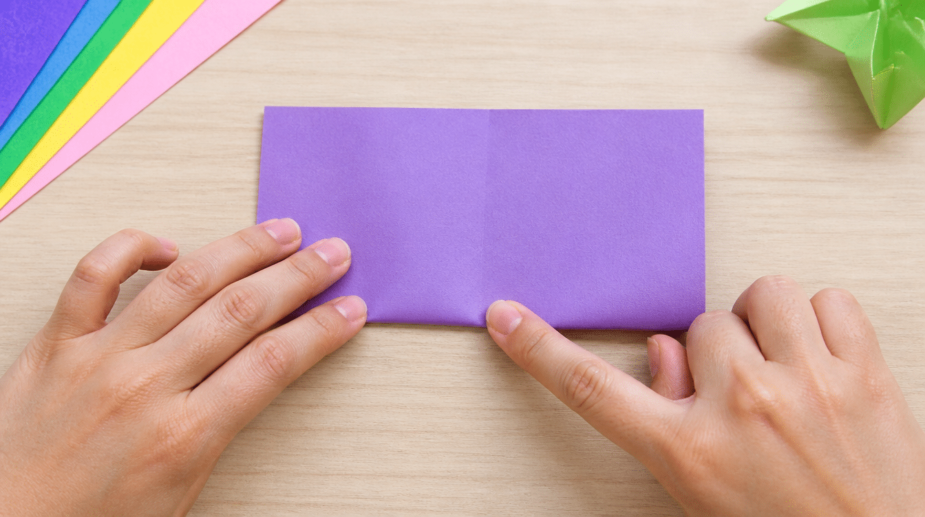 hands folding a purple paper sheet in half on a wooden table with colorful craft paper in the background