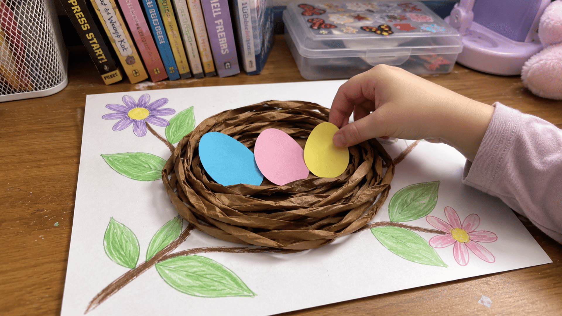 kids bird nest craft with brown paper strips and colorful paper eggs on desk in american home