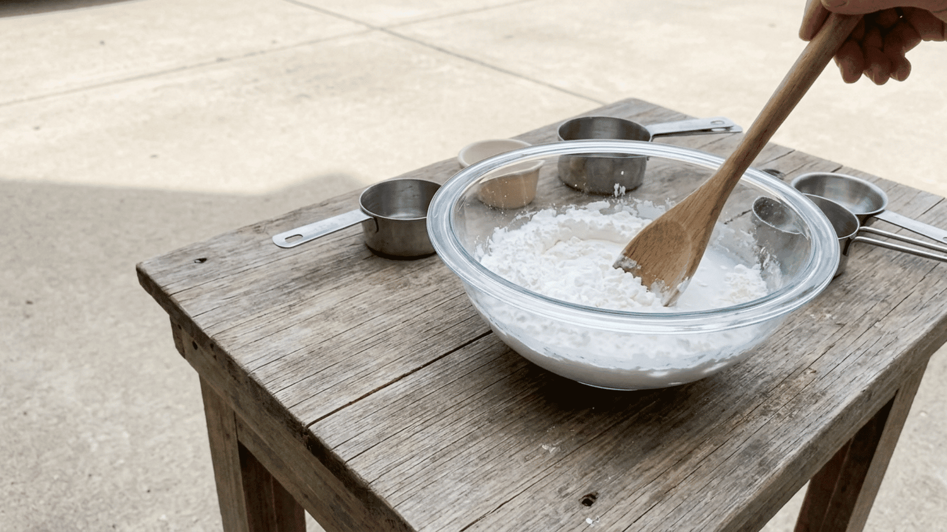 mixing cornstarch and water in a bowl to prepare homemade sidewalk chalk paint with diy supplies