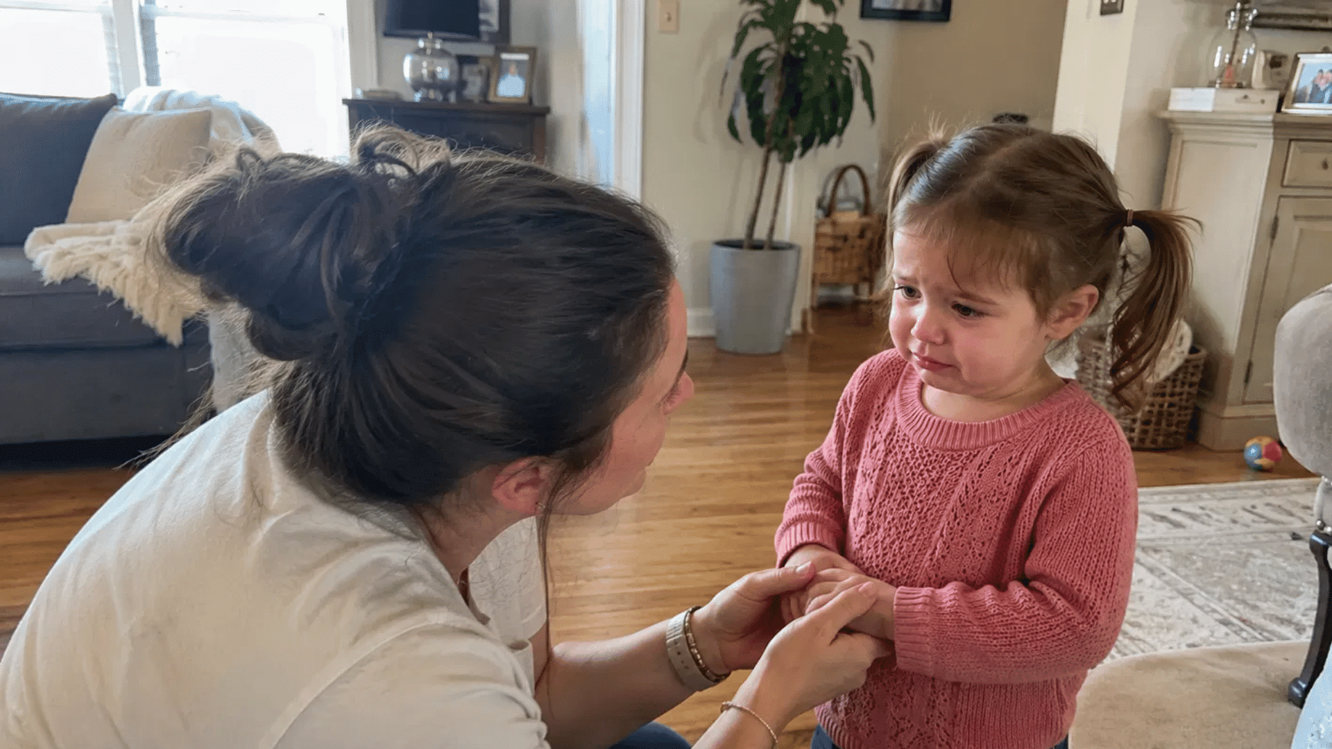 mother comforting toddler during tantrums in cozy living room at home
