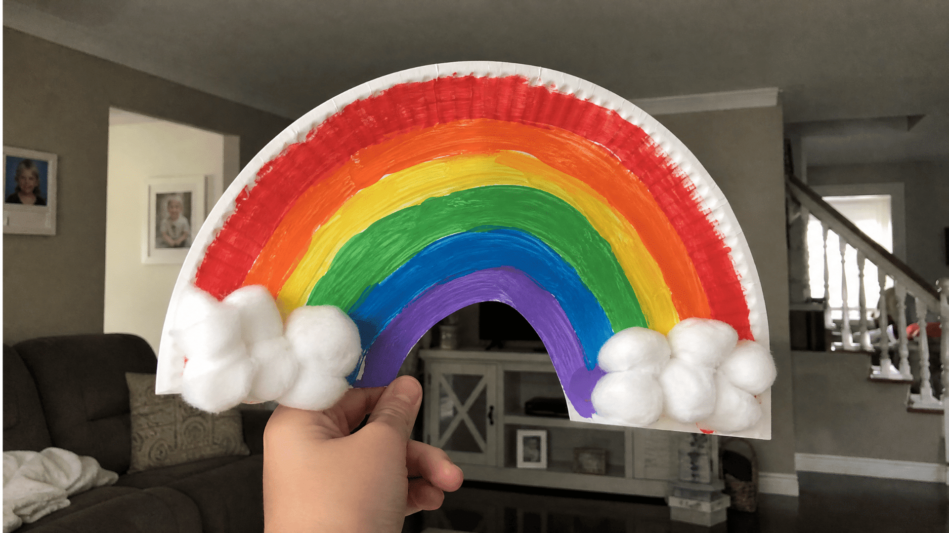 paper plate rainbow craft with cotton ball clouds held up in american home living room
