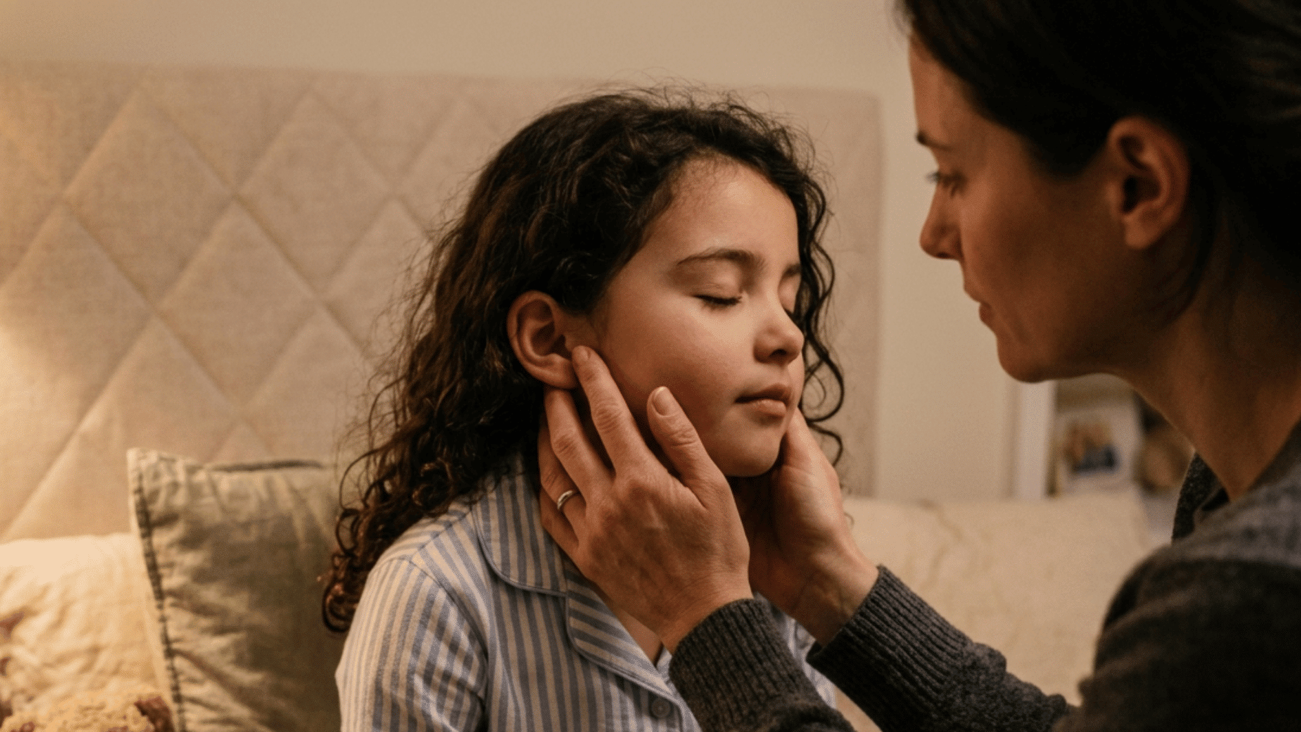 parent gently massaging around child ear to reduce pain in calm nighttime setting