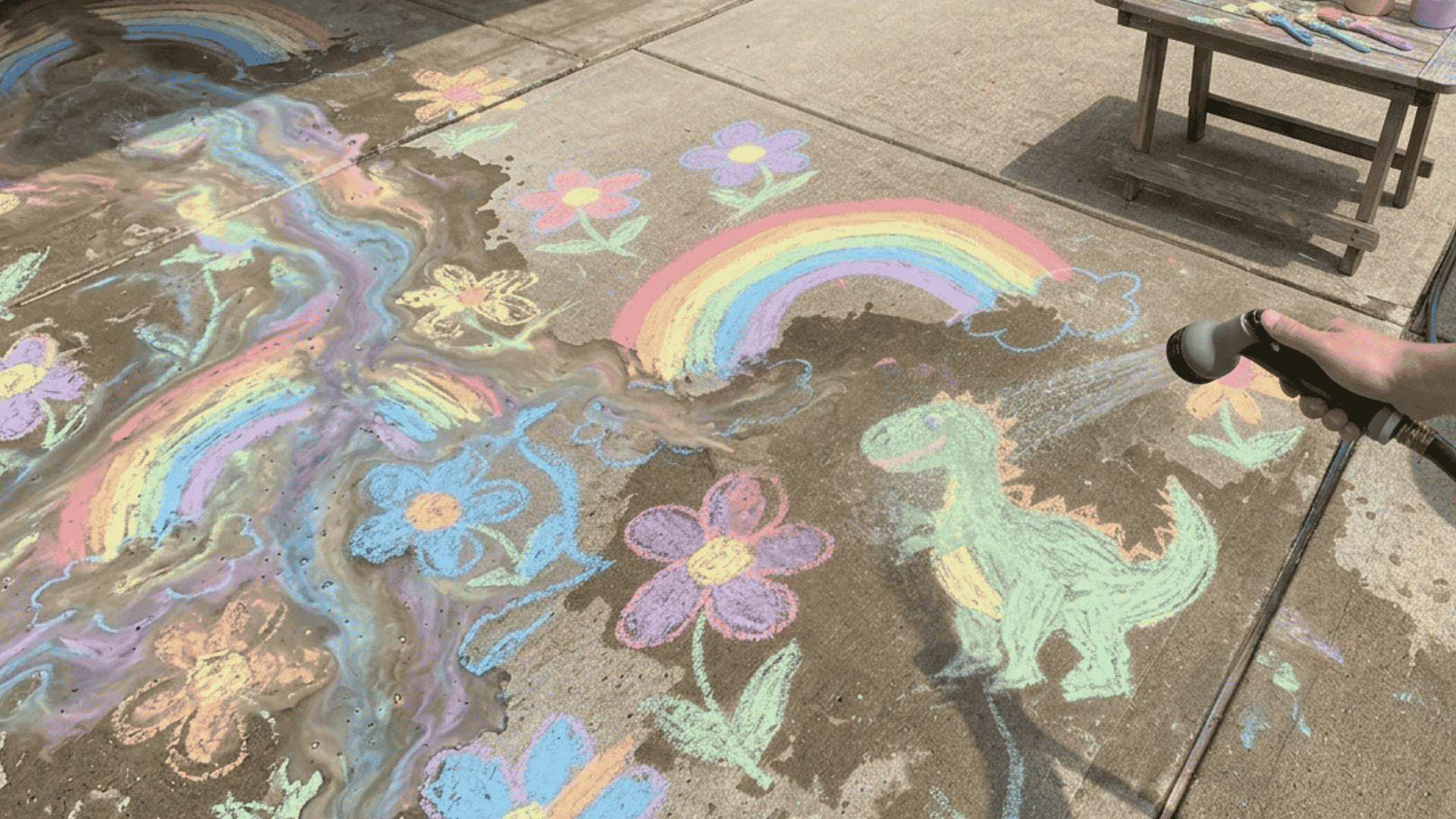 rinsing painted concrete with garden hose during cleanup after diy sidewalk chalk activity