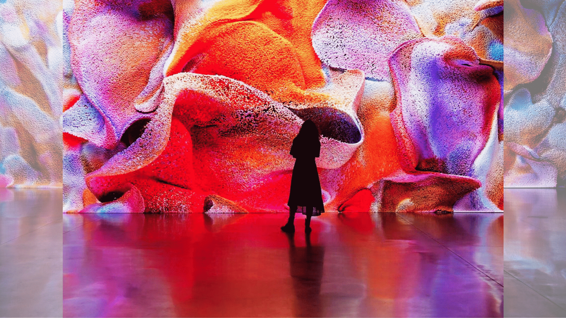 Silhouette of a person standing before a large colorful abstract immersive digital art wall in gallery space (1)