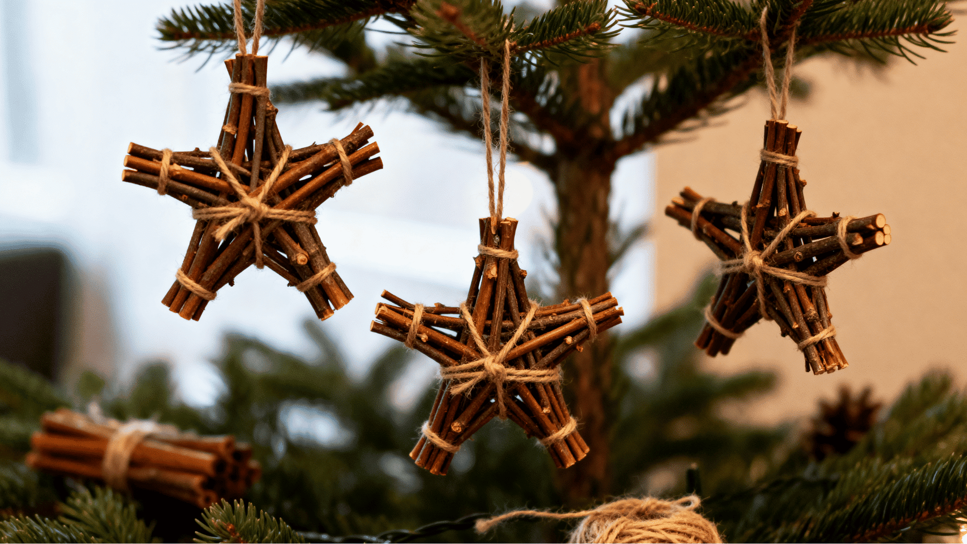 star shaped cinnamon stick ornaments tied with twine hanging on christmas tree branches warm fairy lights cozy rustic holiday scene