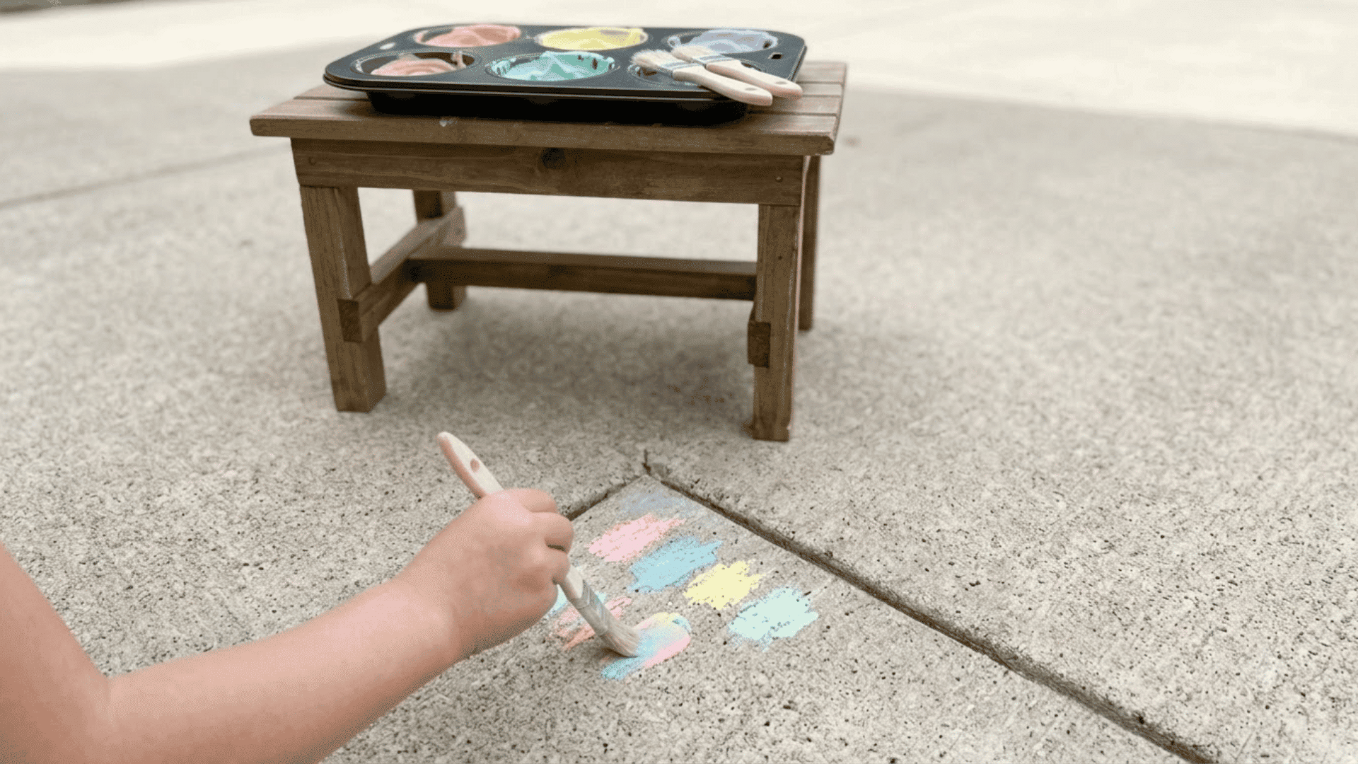 testing colorful chalk paint on a concrete patch before starting the sidewalk art project