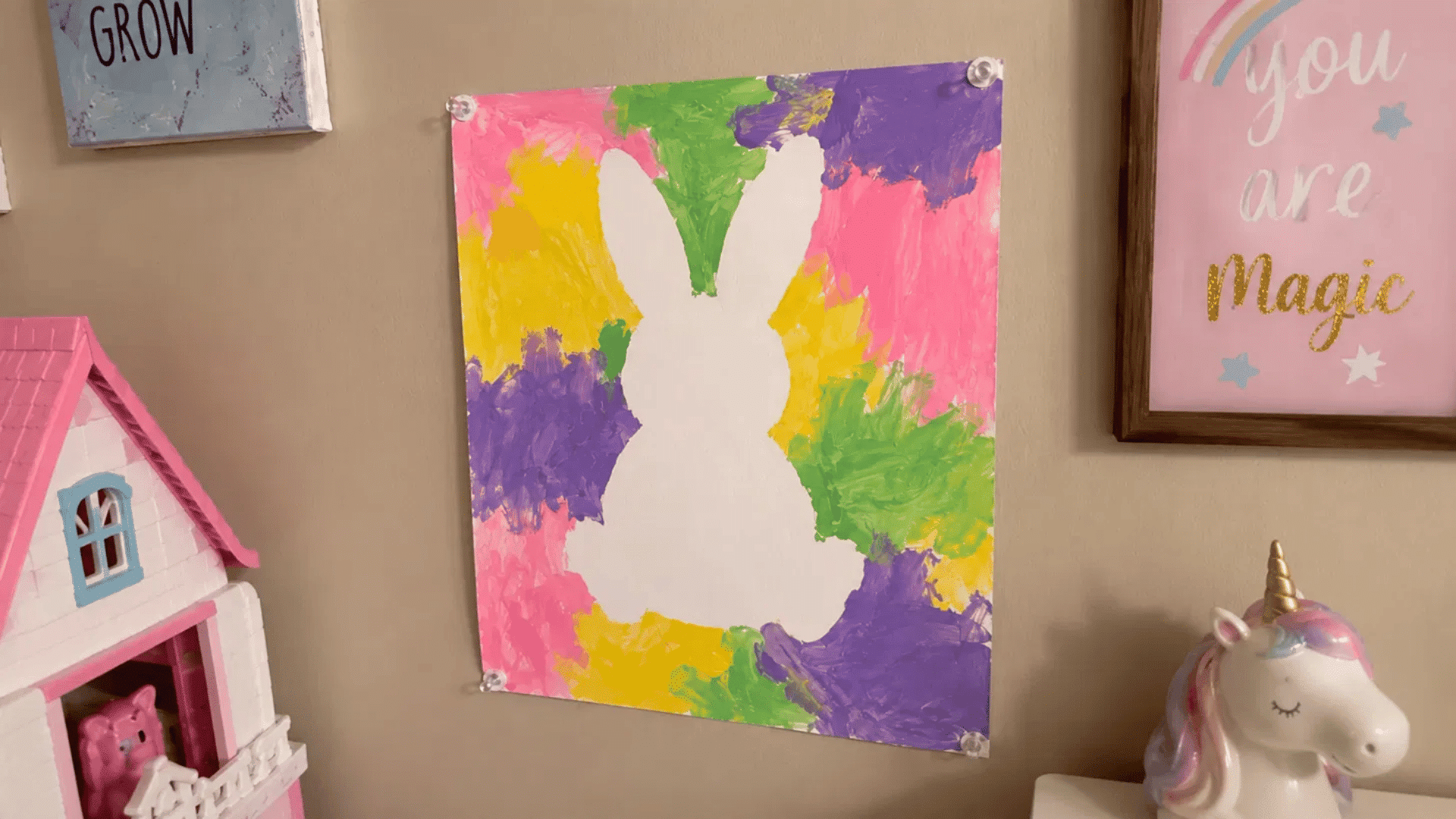 white bunny silhouette painting with colorful painted background hanging on a kid's room wall