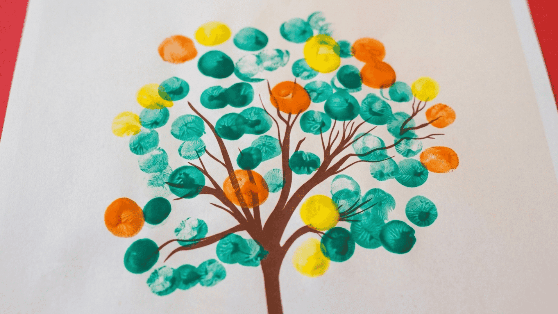 fingerprint family tree craft with colorful thumbprint leaves and family names displayed on white paper