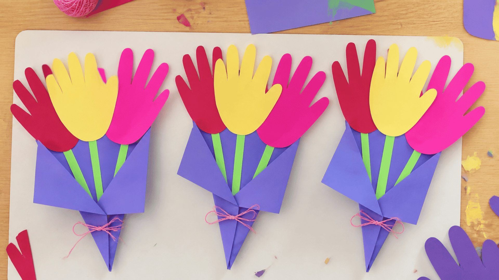 three colorful handprint flowers bouquets arranged on a table for a grandparents day craft activity by children