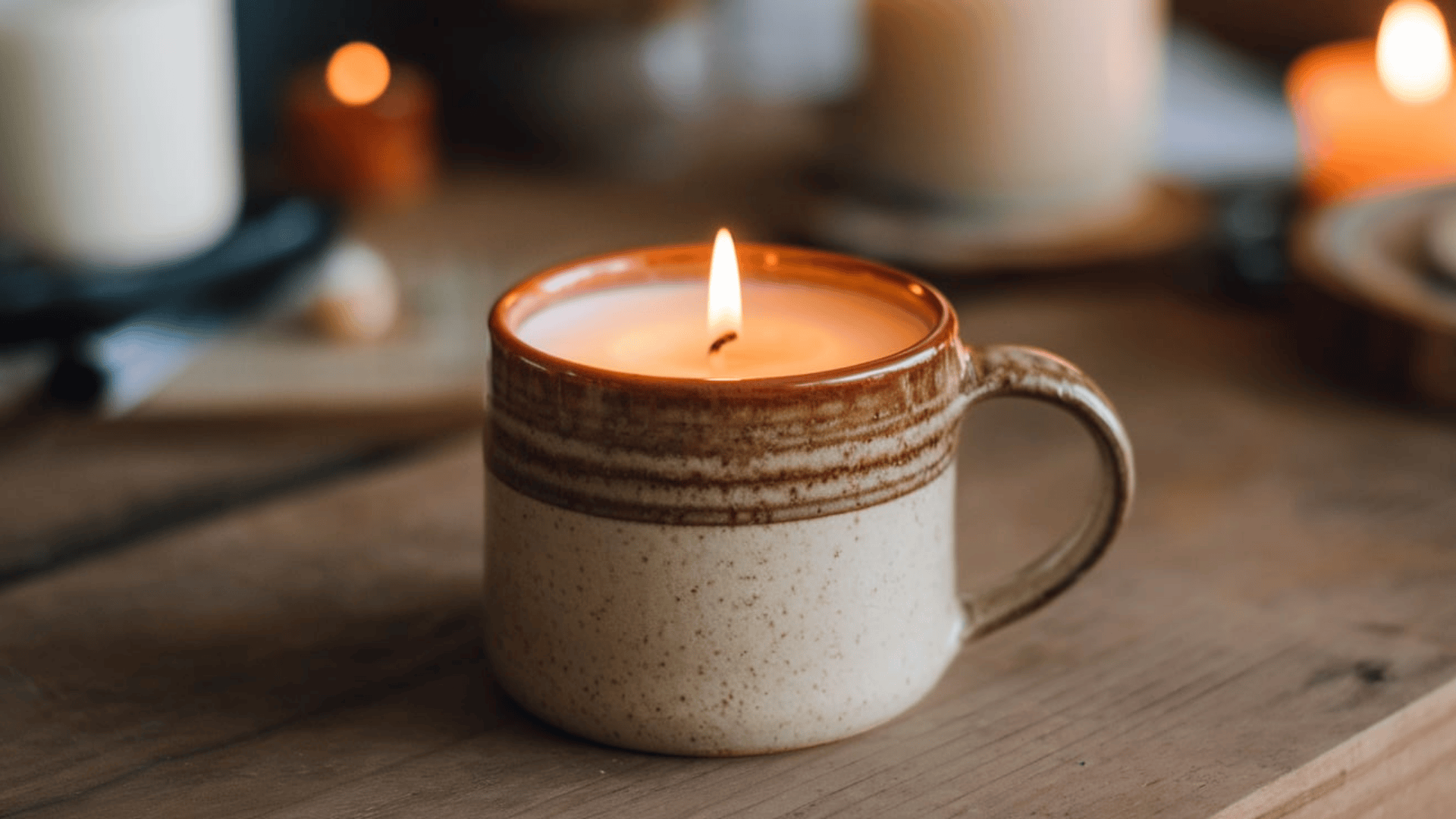 a lit soy candle in a rustic speckled ceramic mug placed on a wooden surface with warm glowing light