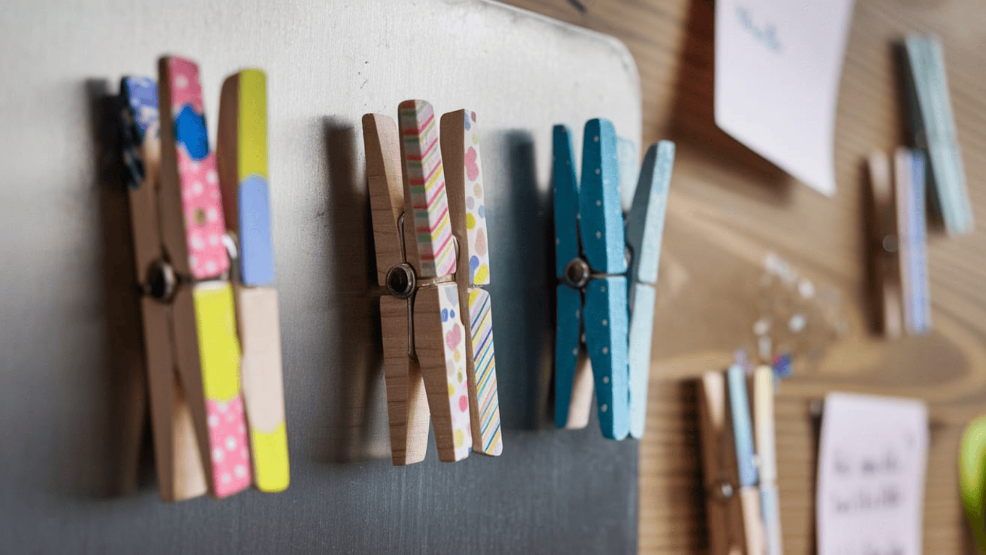colorful decorated wooden clothespins with washi tape patterns used as fridge magnets on a gray surface